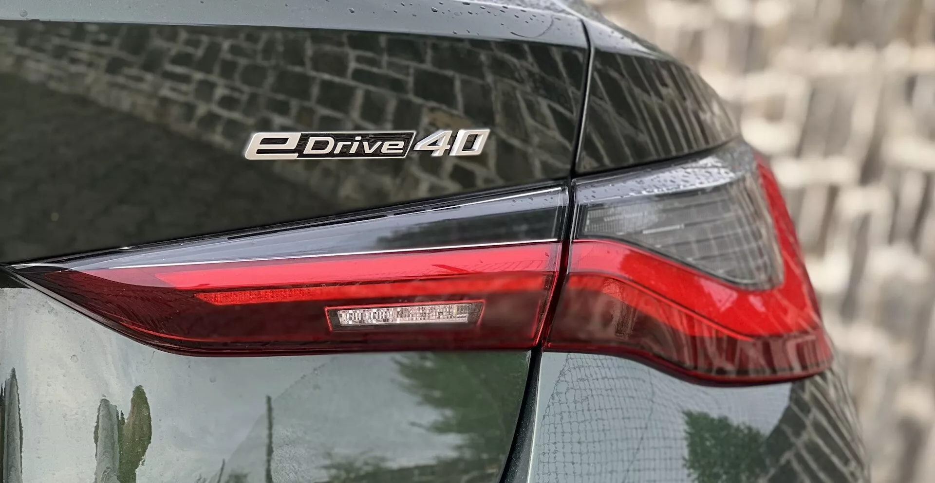 Närbild av bakhörnet på en BMW i4 2021 som framhäver bakljuset och eDrive 40-emblemet med LED-teknologi och reflekterande lack.