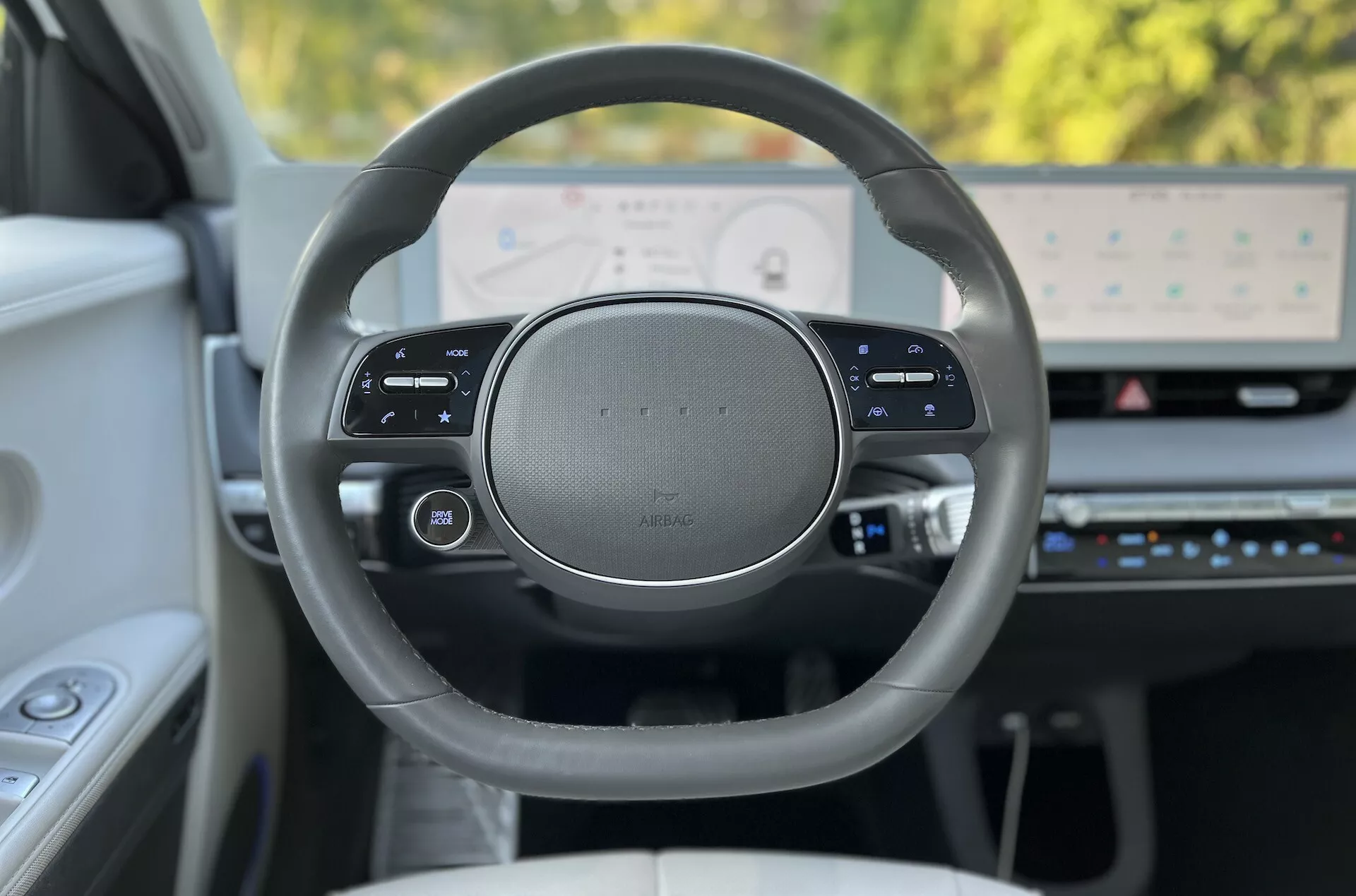 Interiörvy av Hyundai Ioniq-5 2021 som fokuserar på ratten med premiumdesign och högupplöst digital instrumentpanel ur förarens perspektiv, som visar multifunktionella pekkänsliga kontroller och avancerade teknikfunktioner