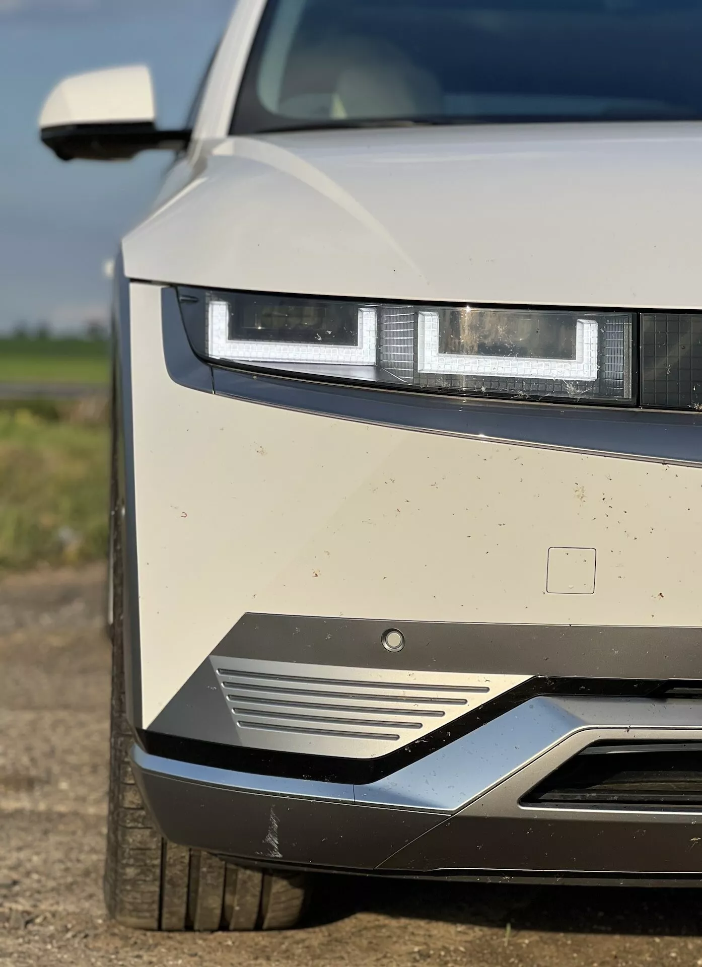Närbild av Hyundai Ioniq 5 2021 som framhäver LED-strålkastare, design på frontgrillen och aerodynamiska egenskaper, med synligt smuts som tyder på nyligen användning
