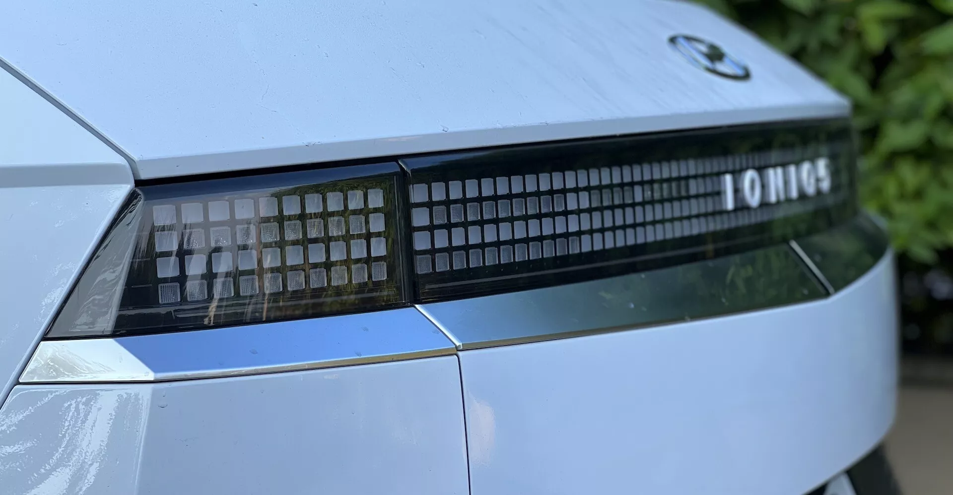 Närbild av en 2021 Hyundai Ioniq-5 som visar upp bakljusen och bagageluckans detaljer från en låg vinkel, framhäver den linjära LED-ljussignaturen och den moderna designen.