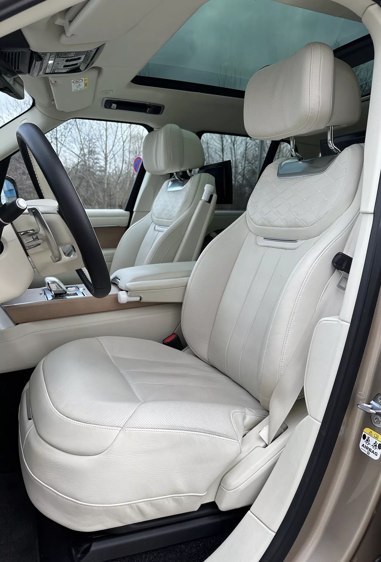 Interiörvy av Land Rover Range Rover 2021 som framhäver förarsidan med lyxiga gräddlädersäten, multifunktionsratt och avancerade kontrolelement på mittkonsolen