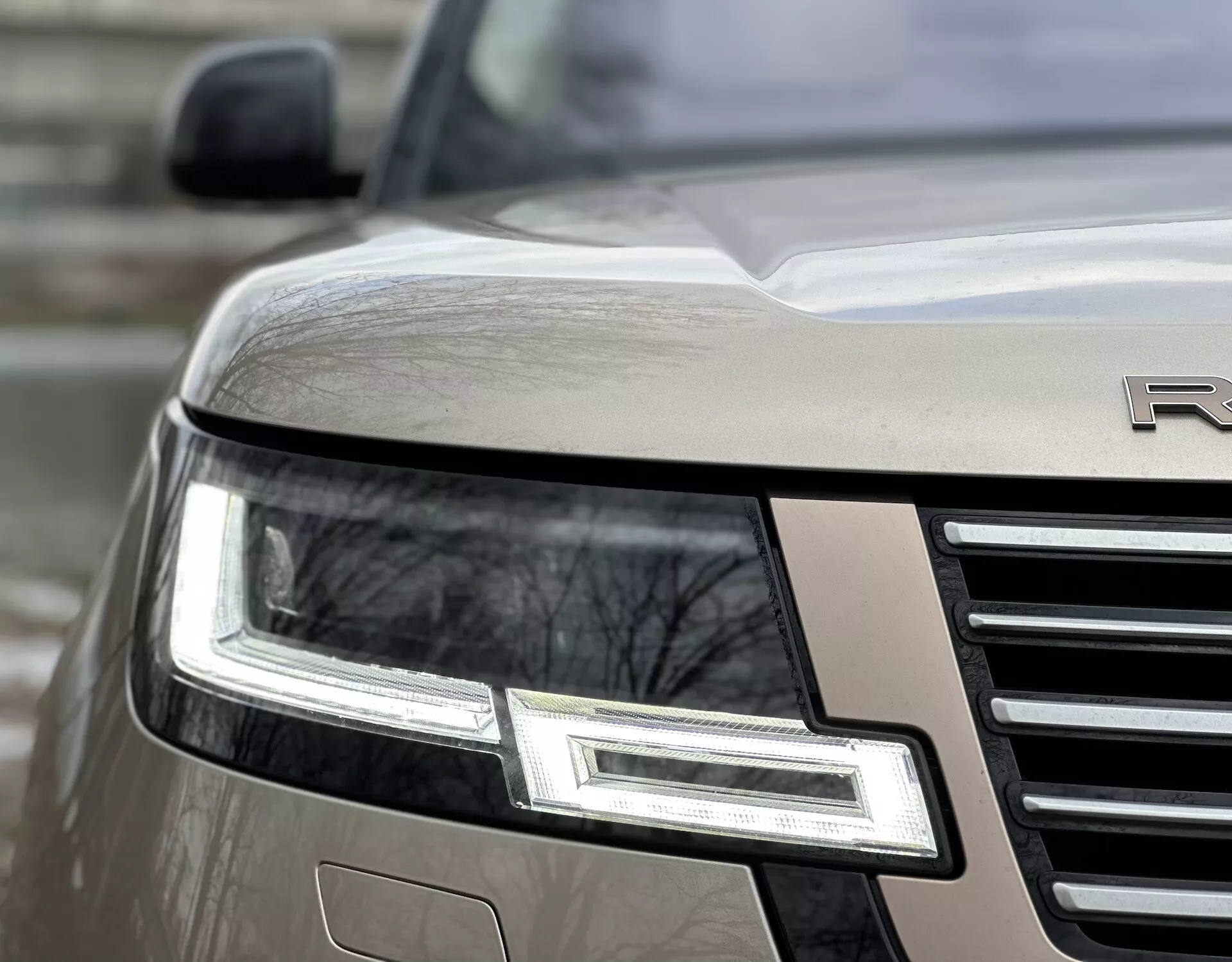 Närbild på vinklat vy av framhörnet på en Land Rover Range Rover 2021 som framhäver LED-strålkastarsamlingen, kromgrillen och partiell emblem på en metallisk kropp