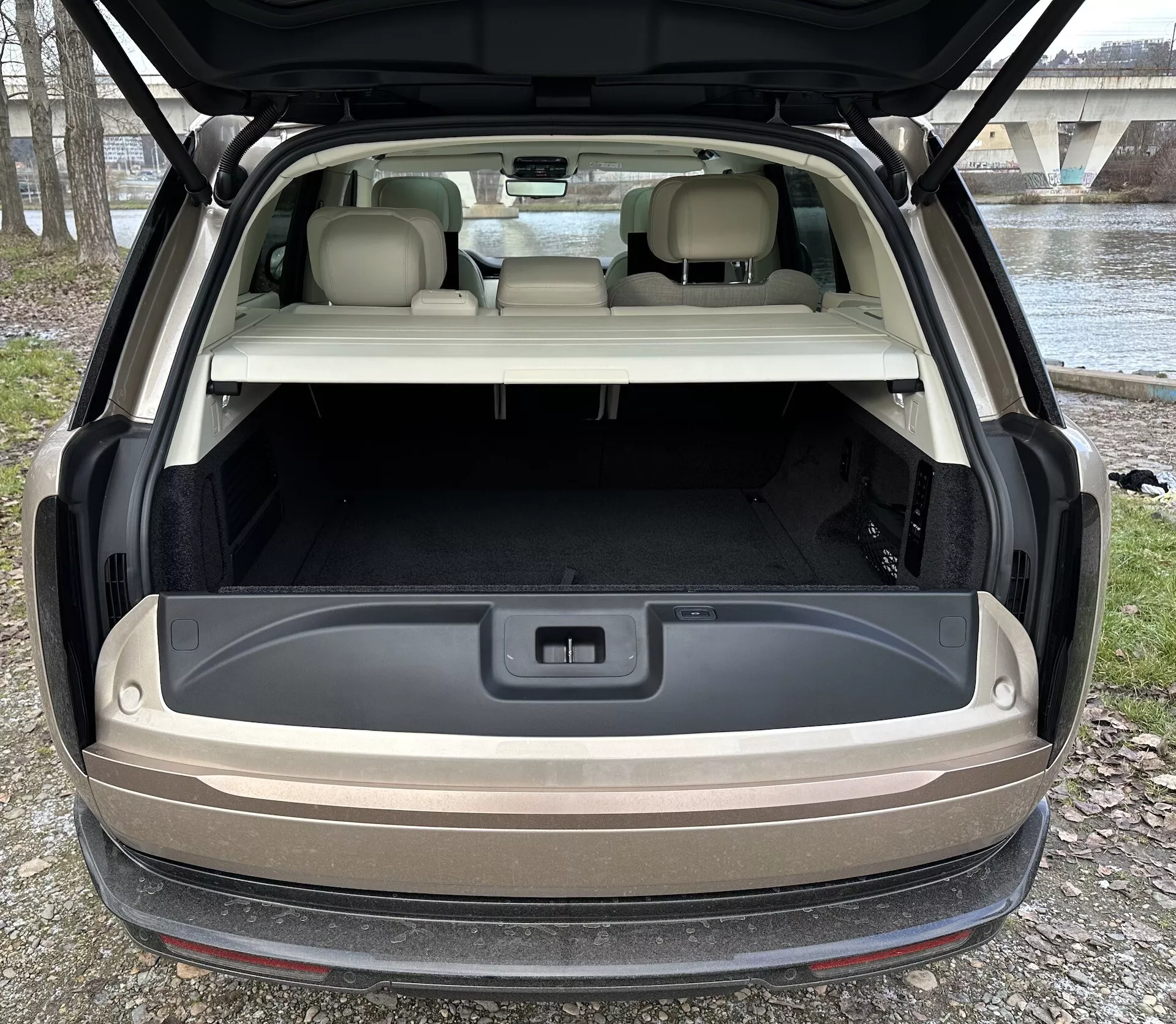 Baksida vy av Land Rover Range Rover 2021 med öppen baklucka som visar rymligt lastutrymme, avancerad belysning och 12-volts uttag mot en naturlig utomhus ljussättning
