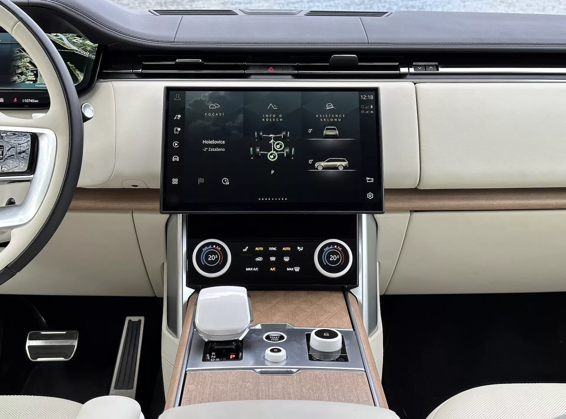 Land Rover Range Rover 2021 med modern interiör, fokuserad på mittkonsolen och infotainmentsystemet med högupplöst pekskärm, luftventiler med kromdetaljer, dubbelzons klimatkontroll, roterande kontrollratt för systemnavigering och lyxiga tvåfärgade lädersäten med detaljer i träslag.