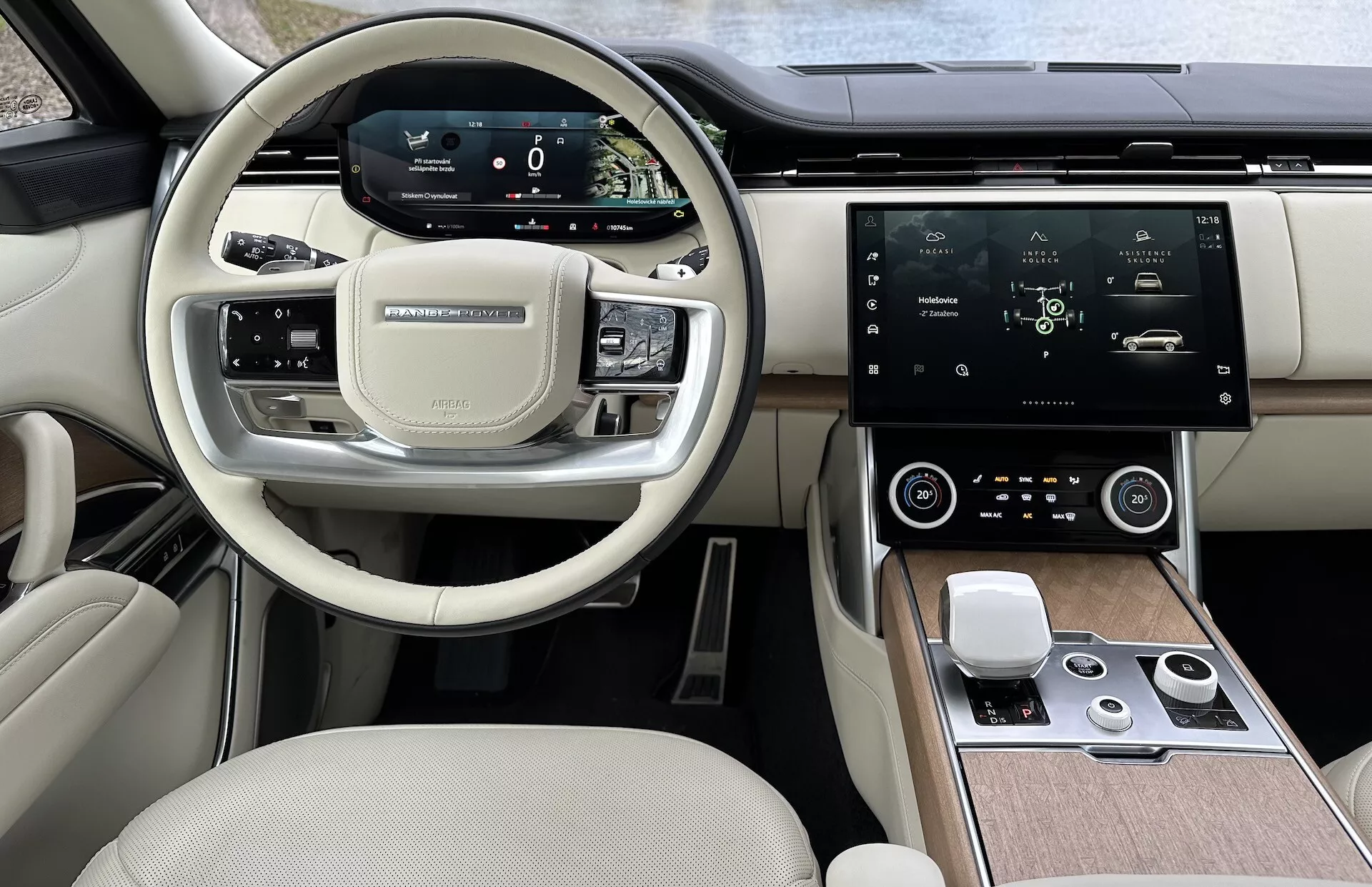 Interiörvy av Land Rover Range Rover 2021 som visar den moderna ratten med multifunktionsknappar, digital instrumentkluster, stor central infotainment-pekskärm, automatisk klimatkontroll och exklusiv tvåtonig kabindesign
