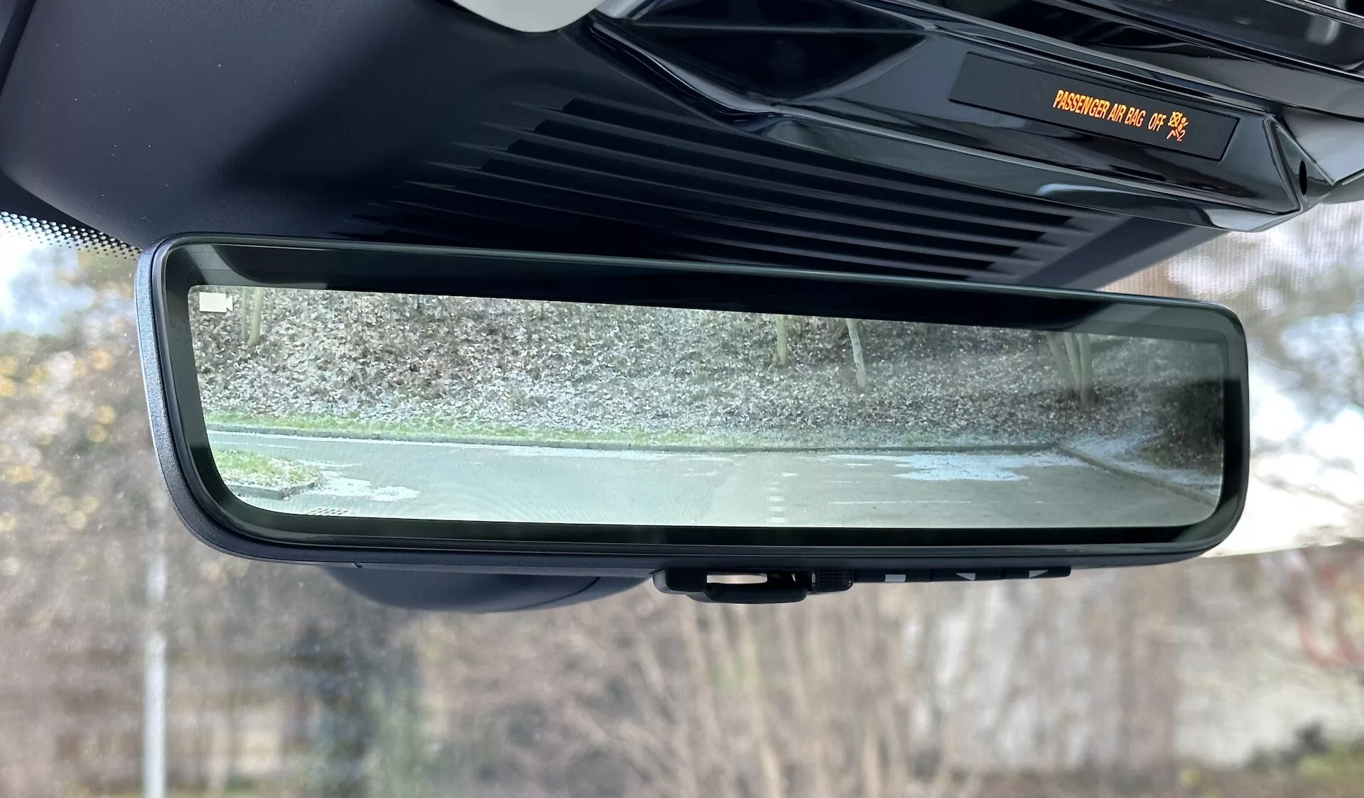 Närbild av den elektrokromiska automatiskt avbländande backspegeln inuti en Range Rover 2021, som framhäver dess ramlösa design, interiörkabinens egenskaper och den reflekterade scenen av stillastående utomhusomgivningar