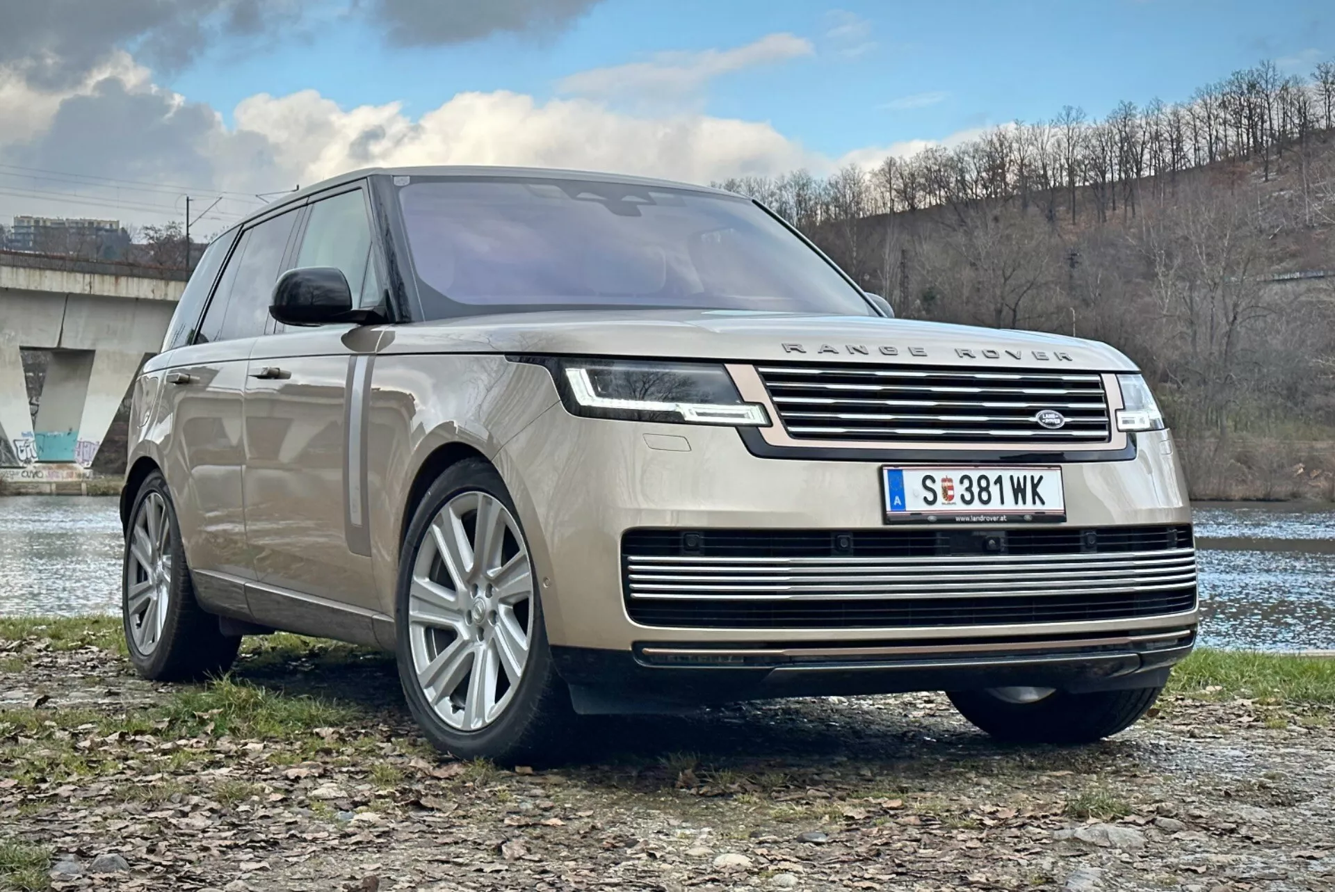 2021 Land Rover Range Rover lyxig SUV, frontalt trekvartsutsikt som visar kromkantad grill, LED-strålkastare, flerspakiga legeringshjul och aerodynamisk design, parkerad utomhus nära en flod och en bro