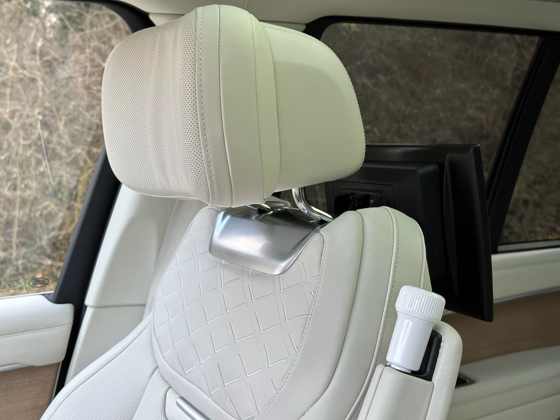 Interiörvy av Land Rover Range Rover 2021 som framhäver passagerarsäte i quiltat kräm-läder med kromat nackstöd och flaskhållare vid dörren, som visar lyxbilsdesign och bekvämlighetsfunktioner