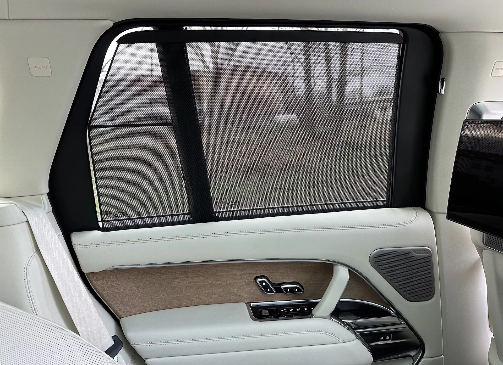 Interiören på höger baksida av en Land Rover Range Rover 2021, med lyxig beige och svart design, träinredning, läderavslut, elektronisk solskärm och avancerade kontrollsystem