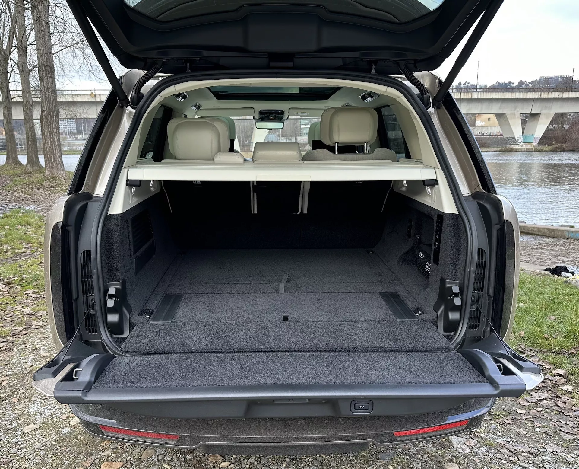 SUV Land Rover Range Rover 2021 som visar rymligt bakre lastutrymme med bakluckan öppen, ljusfärgad klädsel i kontrast mot mörk matta, och interiörfunktioner inklusive lastutrymmets belysning och möjliga sätesvikningsmekanismer