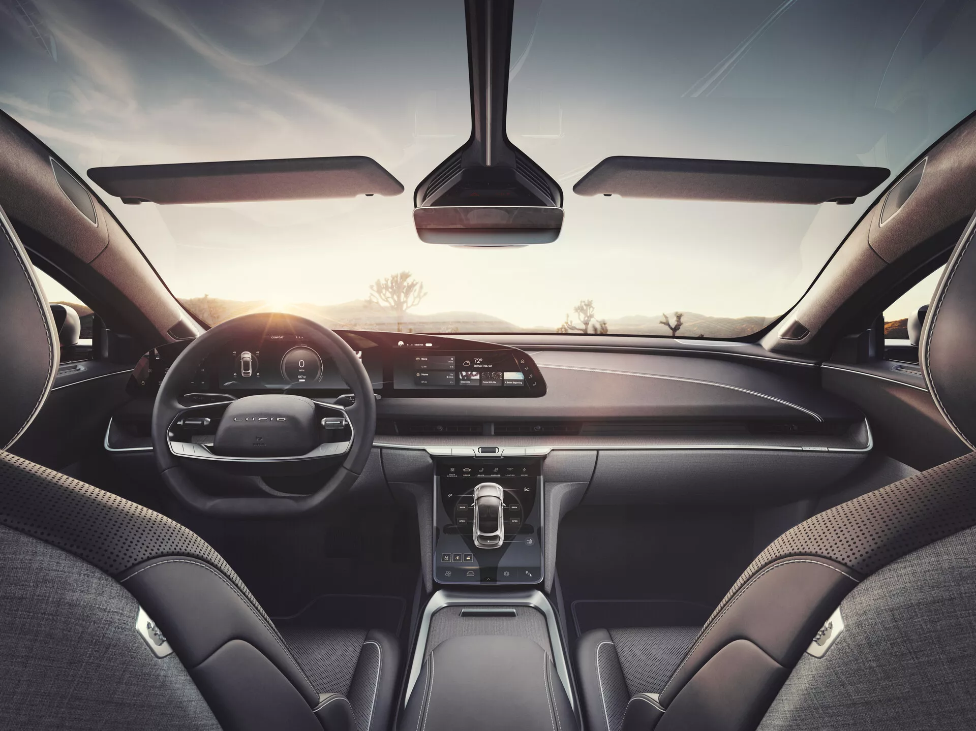 Interiörvy av en Lucid Air 2022-bil från baksätet, som visar instrumentbrädan, infotainmentskärmen, digitala instrumentklustret och läder- och premium-material vilket indikerar en högklassig modell med avancerat mediasystem, klimatanläggningskontroller och anslutningsteknologier.