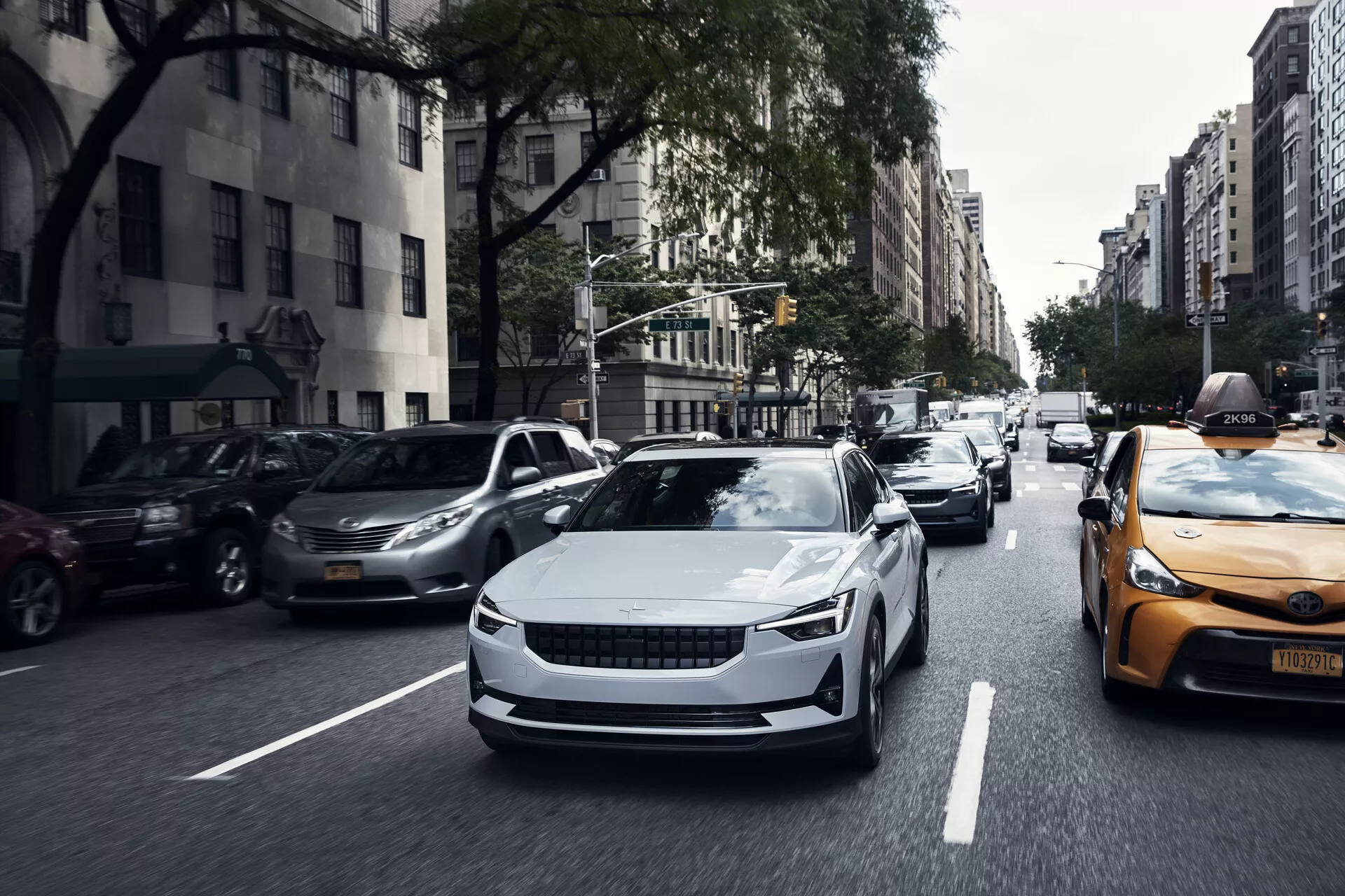 Främre vy av en 2020 Polestar 2 första generationens elbil i rörelse, som visar upp dess eleganta design, aerodynamiska kurvor och moderna LED-strålkastare.