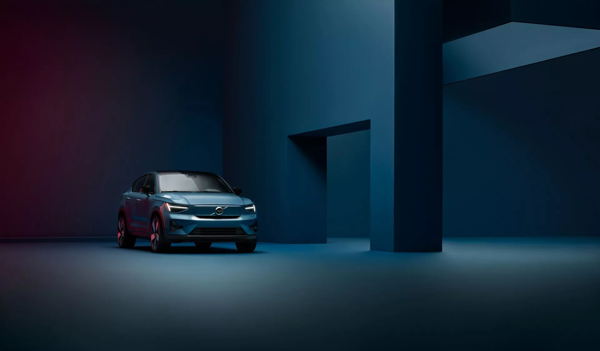 En professionell fotografi av en 2021 Volvo C40 (1:a generationen) från en trekvarts vy framifrån som framhäver den moderna grillen, LED-strålkastarna och den eleganta sidoprofilen i en svagt upplyst, atmosfärisk studiobelysning.