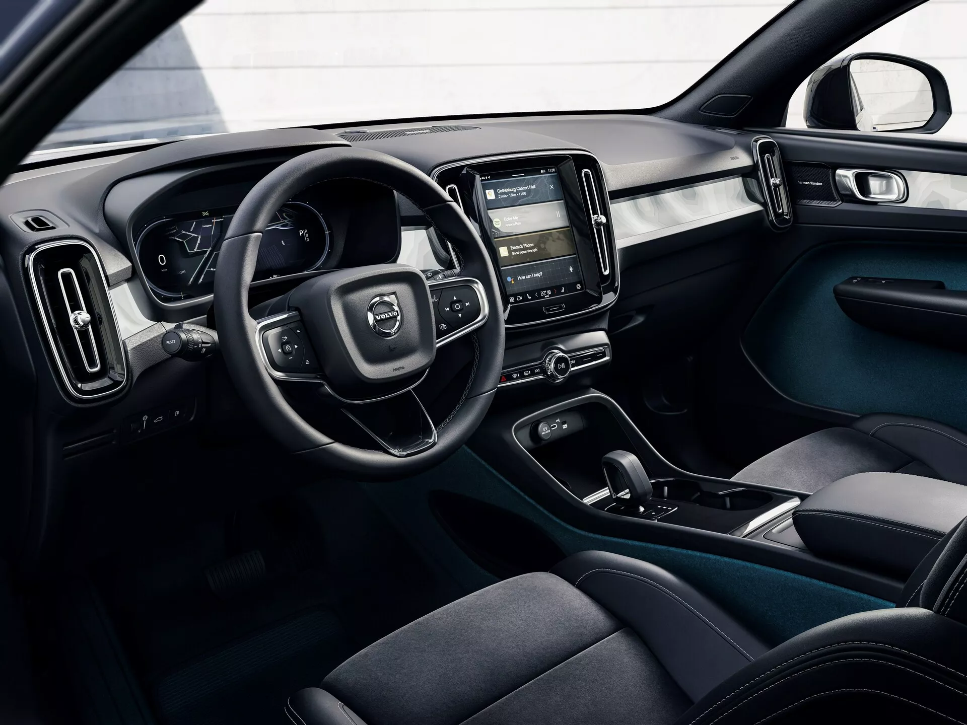 Interiörbild av en Volvo C40 2021 (1:a generationen) från en yttre perspektiv, som visar förarens kupé med ratt, digitalt instrumentkluster, mittkonsol med pekskärmsinfotainmentsystem, klimatkontroller, mörka tygergonomiska säten, dörrkontrollknappar och ett tvåfärgat färgschema med moderna, funktionella designelement.