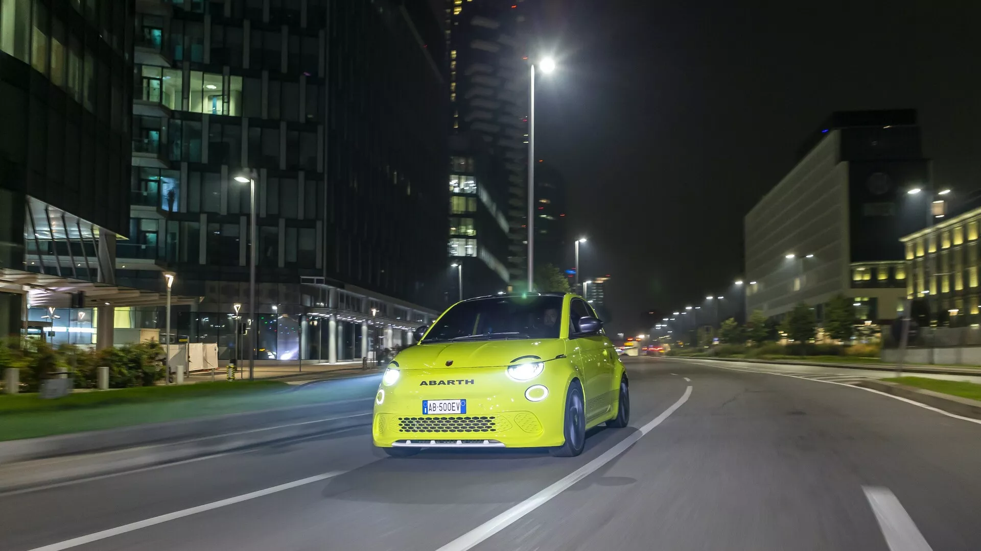 Fotografi av Abarth 500, 595 och 695 (2:a generationen) från 2023 taget ur en front-höger vinkel, som visar dess distinkta främre grill, LED-strålkastare och sportiga designelement. Bilen är stillastående på en stads gata, vilket fångar både de teknologiska funktionerna och den stiliga, kompakta silhuetten som förkroppsligar Abarth-märket.