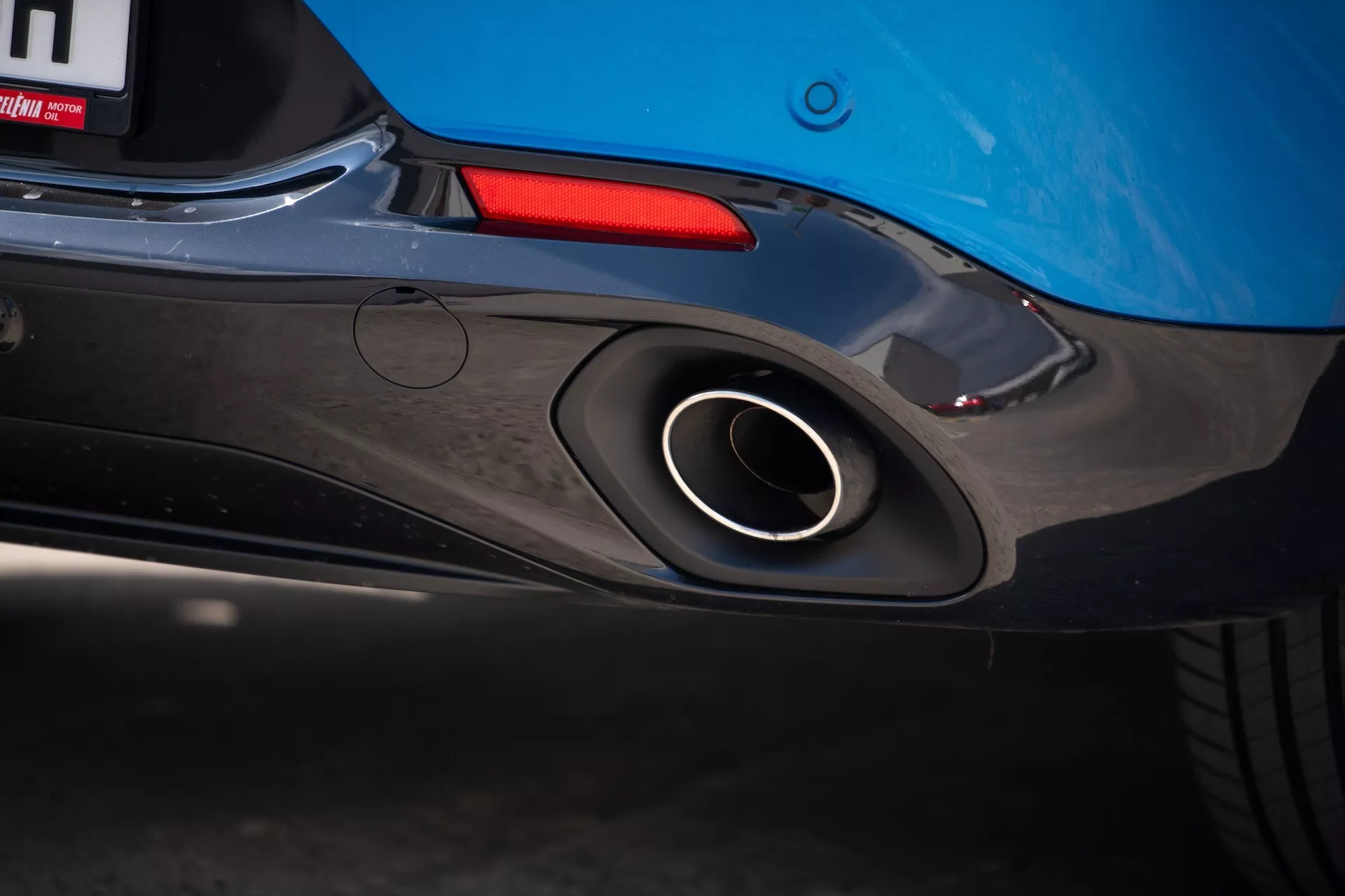Närbild av bakdelen på Alfa Romeo Tonale 2022 som framhäver sportavgasröret, aerodynamisk bakre stötfångardesign och blå karossfärg med en glimt av bakljuset