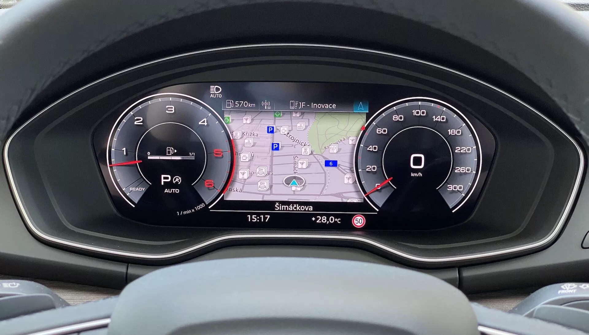Förarvy av den moderna instrumentpanelen i Audi Q5 Sportback 2020 som visar instrumentklustret med två analoga mätare och en central digital display som visar en GPS-karta, temperaturavläsning, bränsleförbrukning, körlägesindikatorer och tid i en högupplöst färggränssnitt.