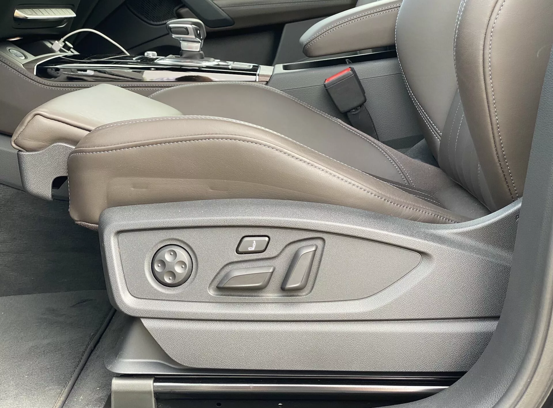 Interiörvy av Audi Q5 2020 Sportback som visar förarsätet i ljusbrunt/beige läder med elektroniska justeringskontroller, vilket framhäver lyx och avancerad sittteknik, inklusive potentiella minnesinställningar; bilden tagen i vinkel från utsidan av förardörren.