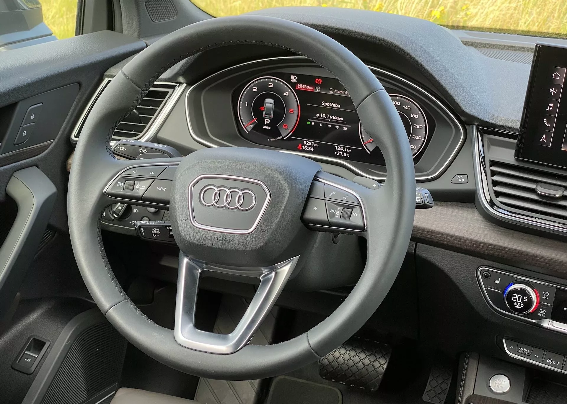 Audi Q5 2020 Sportback-interiör från förarens perspektiv som visar ratt med multifunktionskontroller och Audi-emblem, digital instrumentpanel med hastighetsmätare, varvräknare, central infotainmentdisplay och HVAC-kontroller, med mjuka, premium-material.