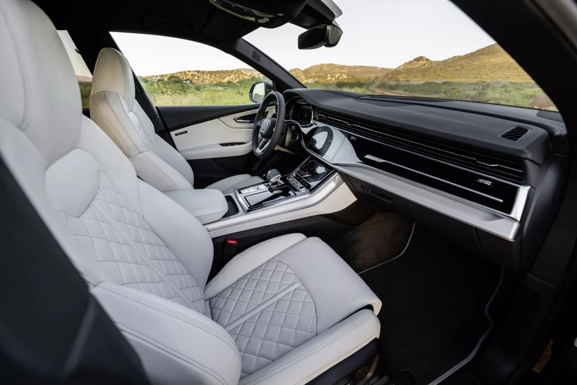 Interiör i Audi Q8 2023 (4M-Facelift) som visar vita kviltade lädersäten, högkvalitativ mittkonsoldesign, expansiv pekskärmsinfotainmentsystem och moderna, ergonomiska funktioner taget från passagerarsidan