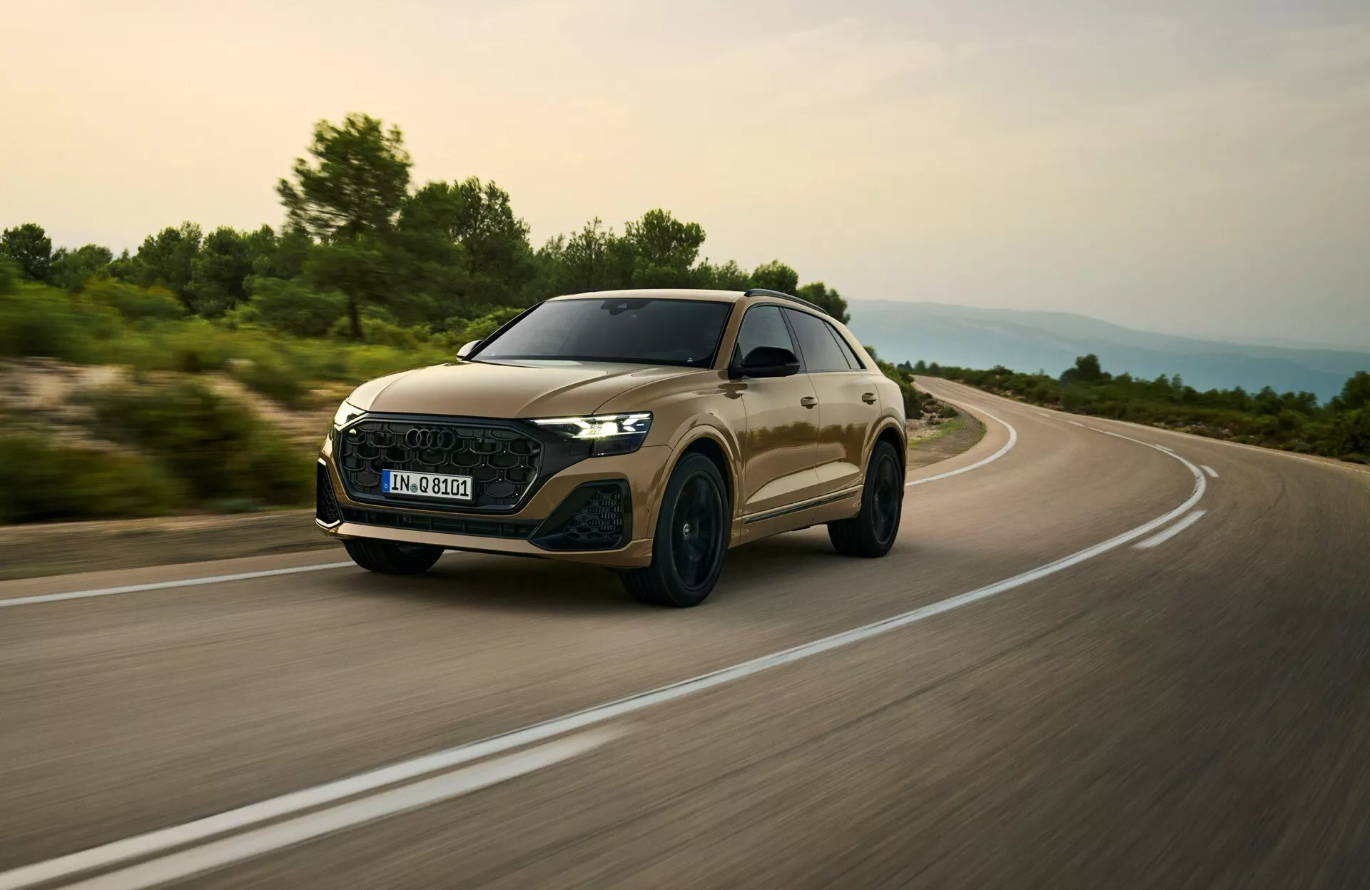 Audi Q8 2023 (4M facelift-modell) fångad i en dynamisk körning, fokuserar på dess aerodynamiska frontgrill, LED-strålkastare och slanka profil från ett lågt framifrån trekvarts vinkel som antyder hastighet och premiumfunktioner