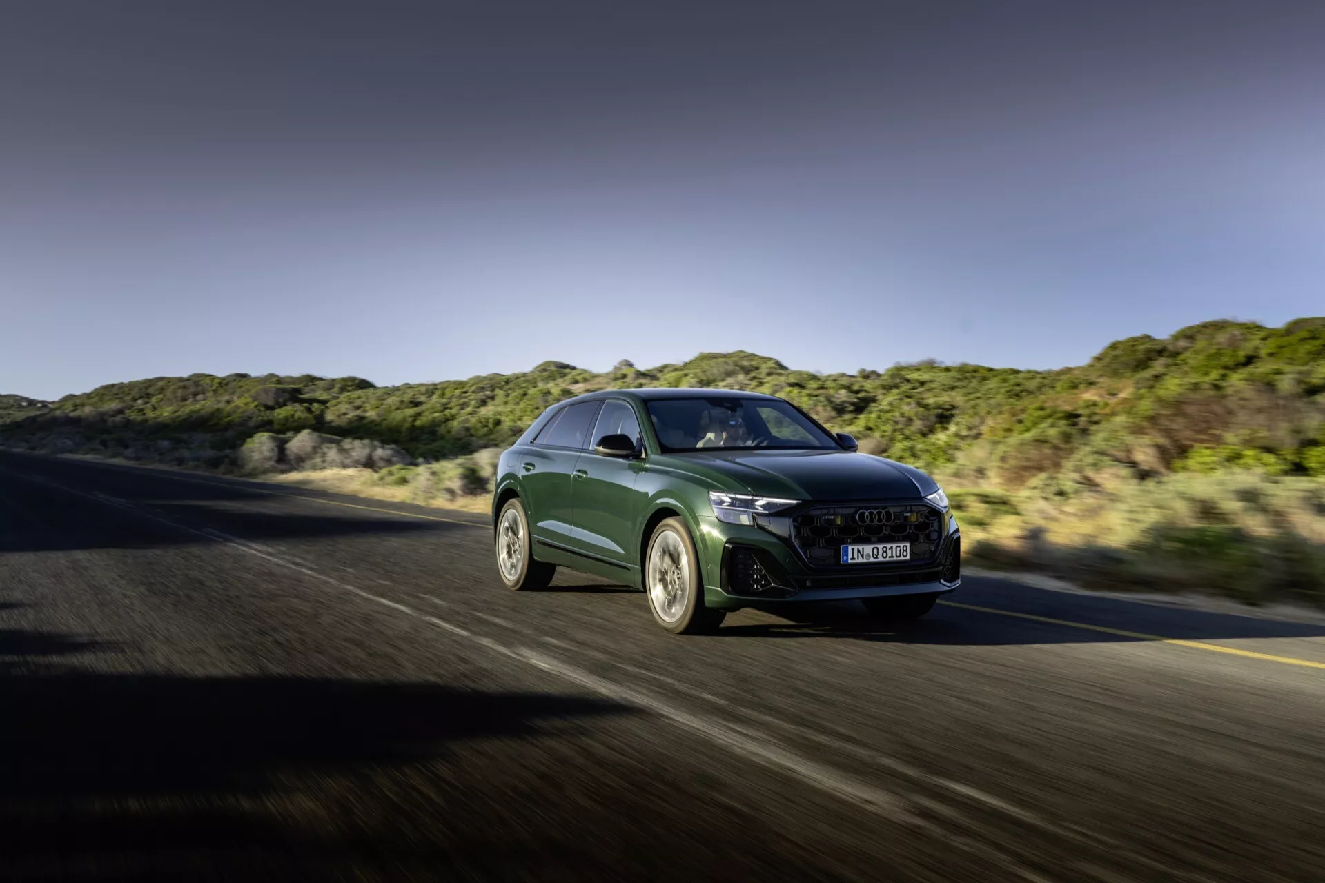 Audi Q8 2023 (4M-Facelift) i rörelse, visar aerodynamisk form, skarpa LED-strålkastare, stor grill med avancerad kylning, sportiga legeringshjul och högprestanda funktioner från en främre trekvarts vinkel på en motorväg