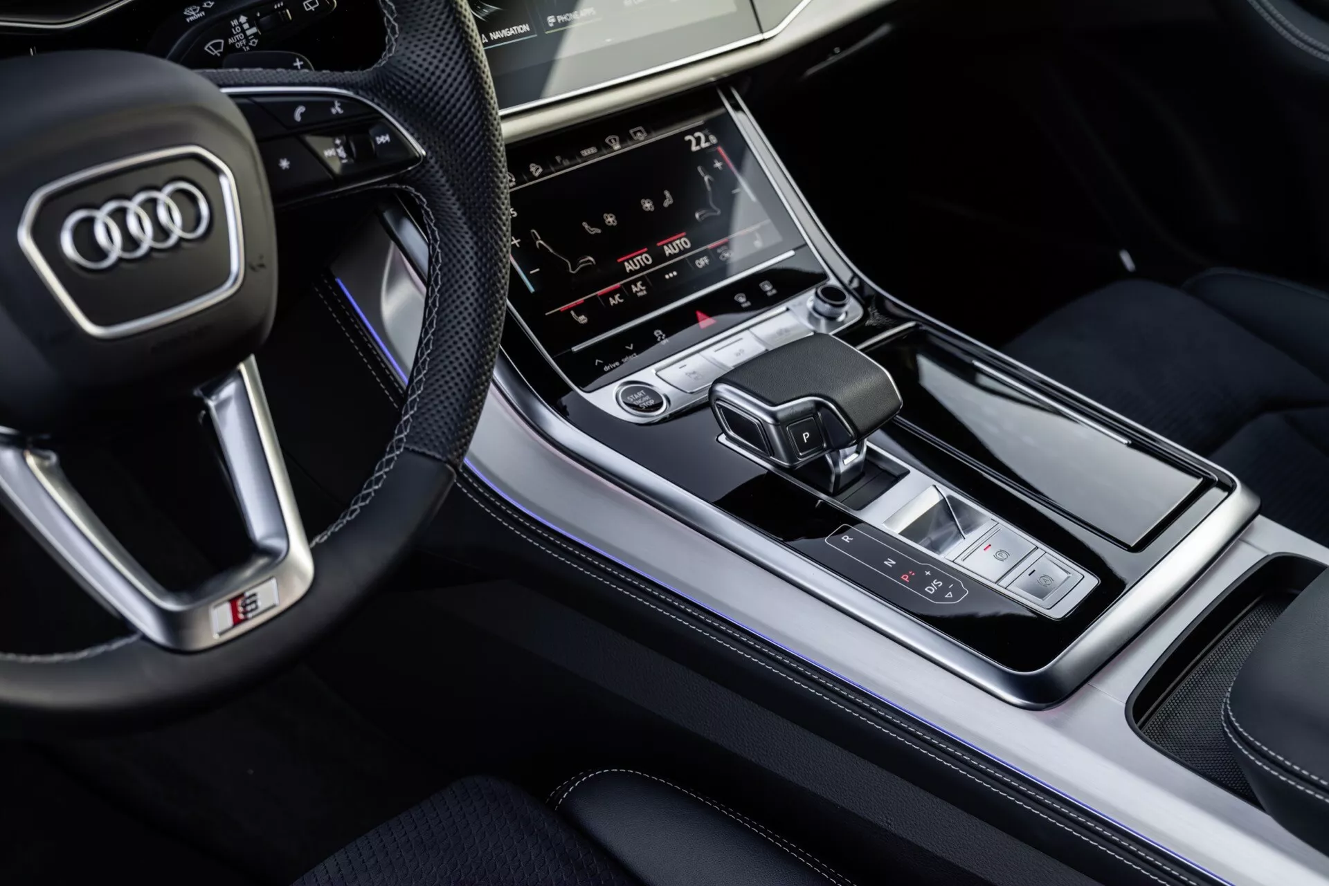 Översiktsvy av Audi Q8 2023 interiör med fokus på mittkonsolen med växelspak och multimedia kontrollpanel, som framhäver lyxiga avslutningar och avancerade teknologiska funktioner