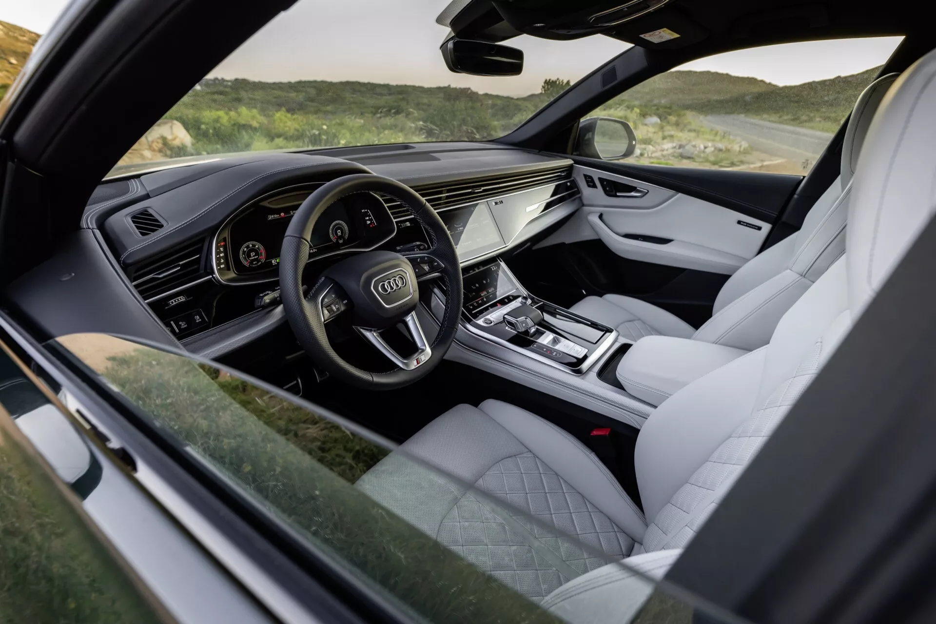 Interiörvy av Audi Q8 2023 (4M-Facelift) som framhäver förarsidans cockpit med digital instrumentkluster, pekkänsligt infotainmentsystem och lyxiga avslut som läderklädsel och metallackcenter