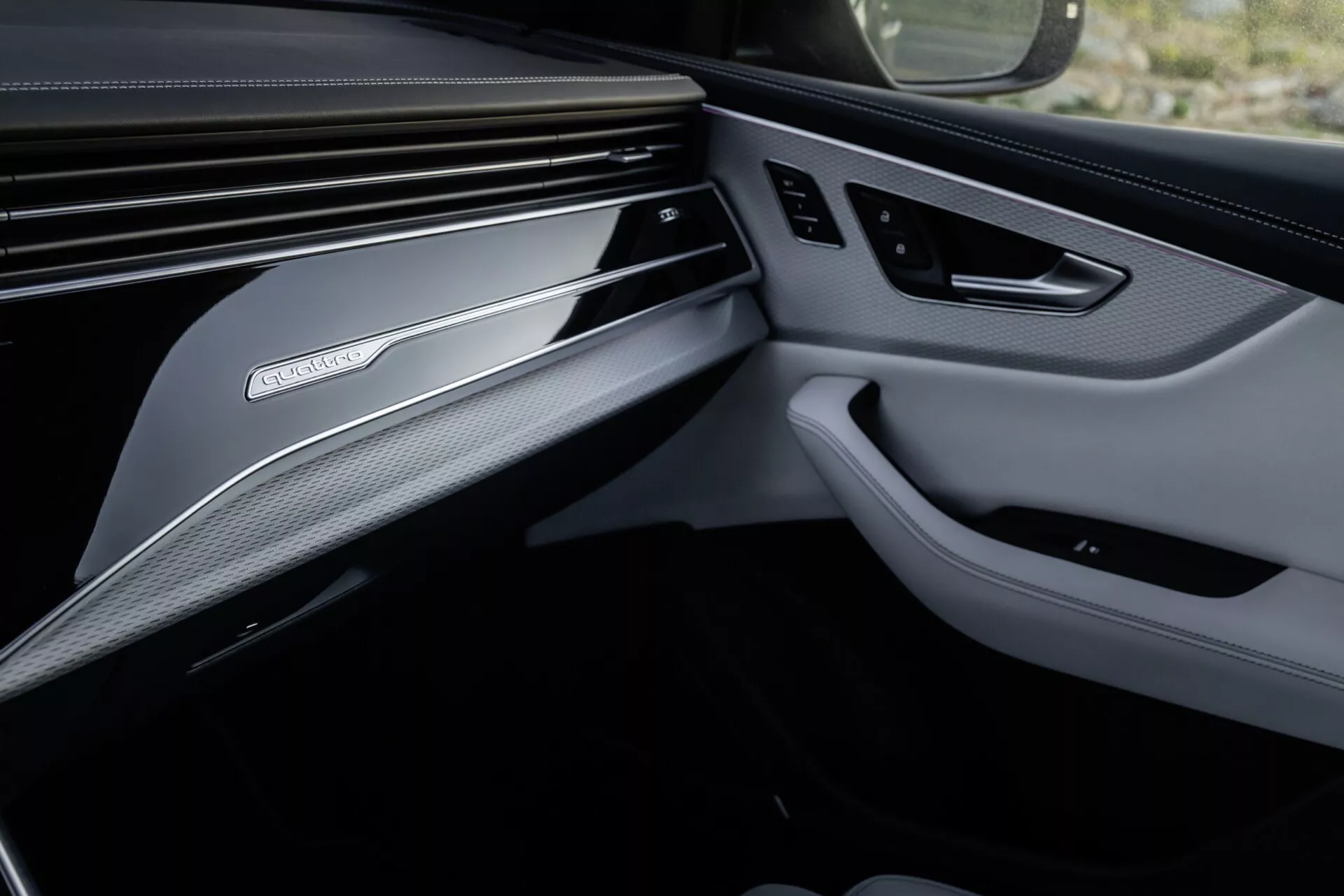 Interiörbild av Audi Q8 2023 (4M-Facelift) som fokuserar på den lyxiga designen på framsidan av passagerarsidan, inklusive en detaljerad vy av instrumentbrädan och dörrpanelen med premiummaterial och tekniska funktioner