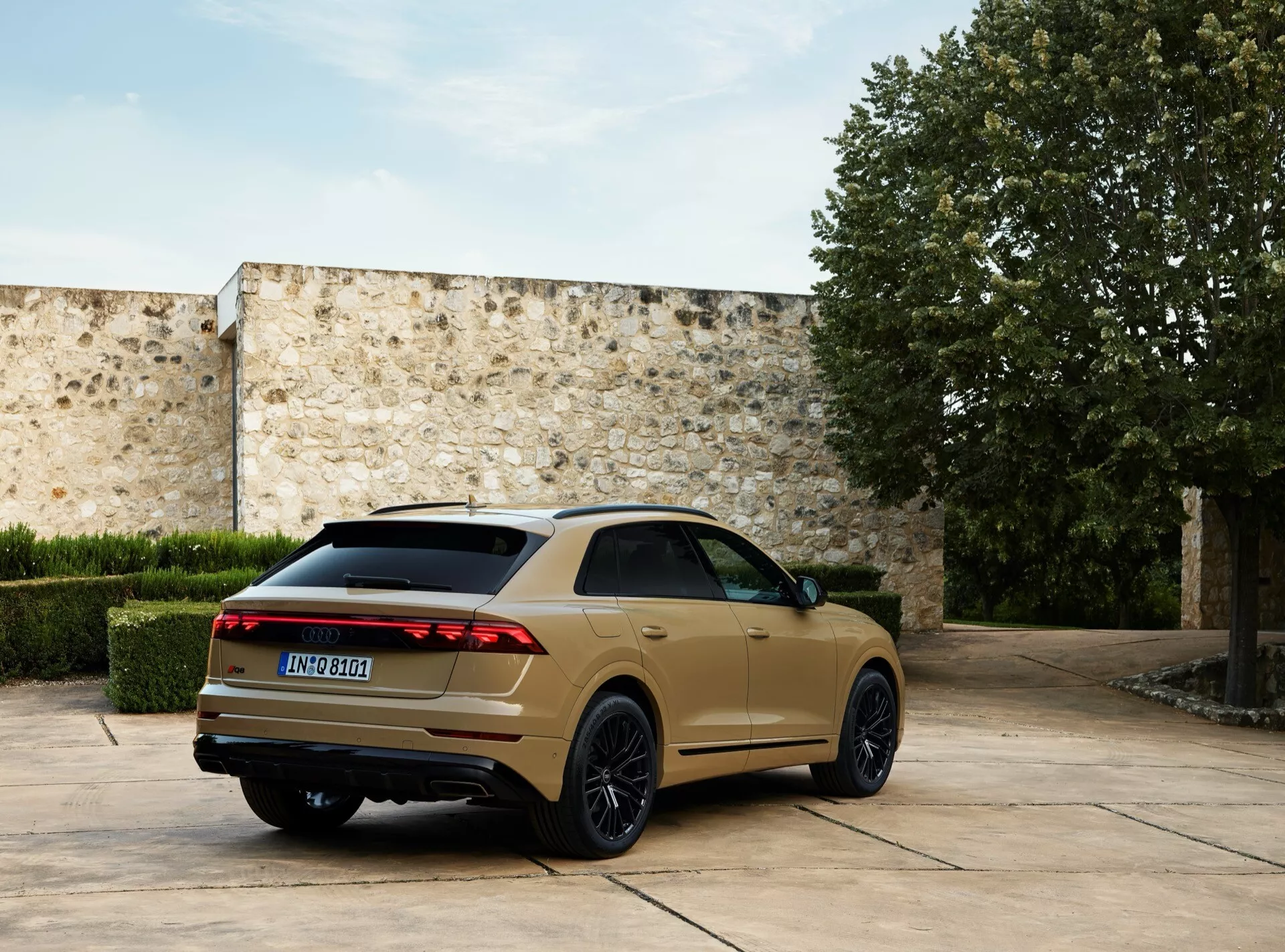 2023 Audi Q8 4M facelift modell parkerad utomhus, fångad från en tre kvartal bakifrån vinkel som framhäver dess LED-bakljus, mörka flerspakiga lättmetallfälgar, sluttande taklinje och dubbla avgasrör mot en bakgrund av en stenlagd gård