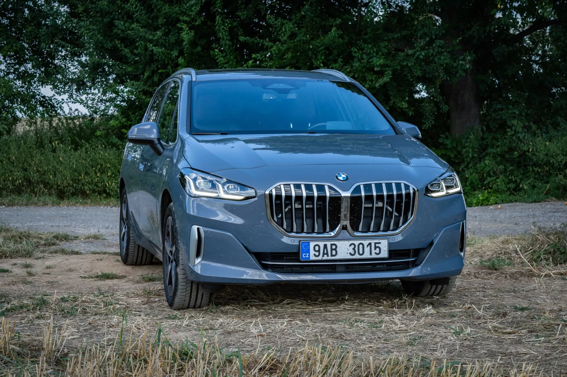 Blå BMW 2-serie Active Tourer SUV från en framifrån tre fjärdedels vinkel som visar den ikoniska njurgrillen, LED-strålkastare, frontstötfångare med dimljus och luftintag, lättmetallfälgar och en del av dess metalliska blå sidokaross