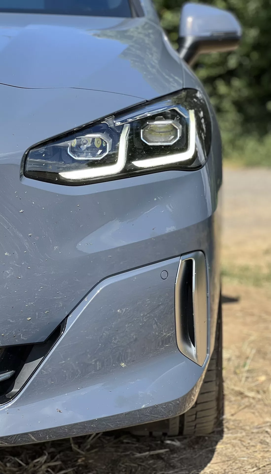 Närbild av BMW 2-serien Active Gran Tourer 2022:s främre vänstra sida som visar LED-strålkastare och aerodynamisk stötfångare med parkeringssensor, vilket visar avancerad teknik och design.