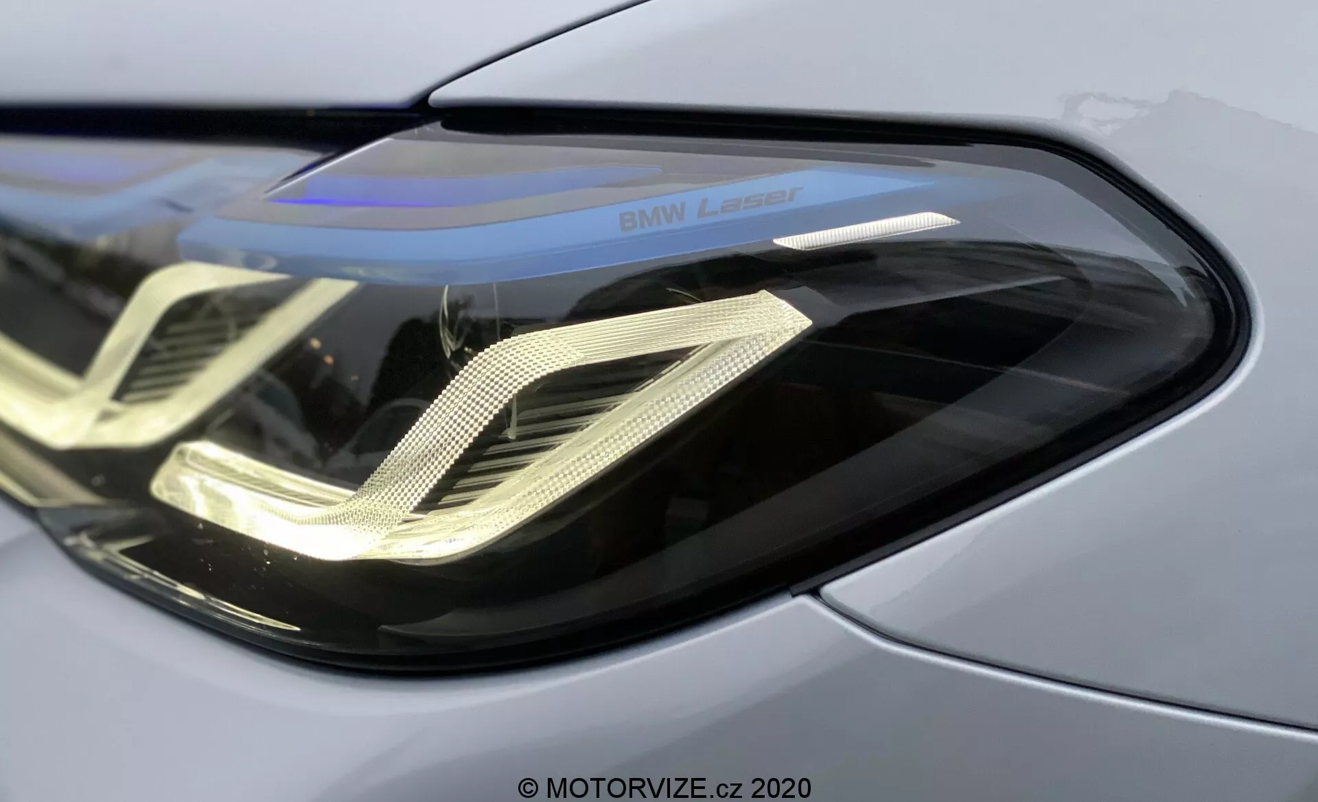 Närbild av främre vänstra strålkastaren på 2020 BMW 520i Touring Steptronic, med elegant böjd polykarbonatlins, distinktivt dubbelhelix LED-varselljus, reflekterande hölje och 'BMW Laser'-markering, som framhäver avancerad laserteknik och premium metallisk kaross.