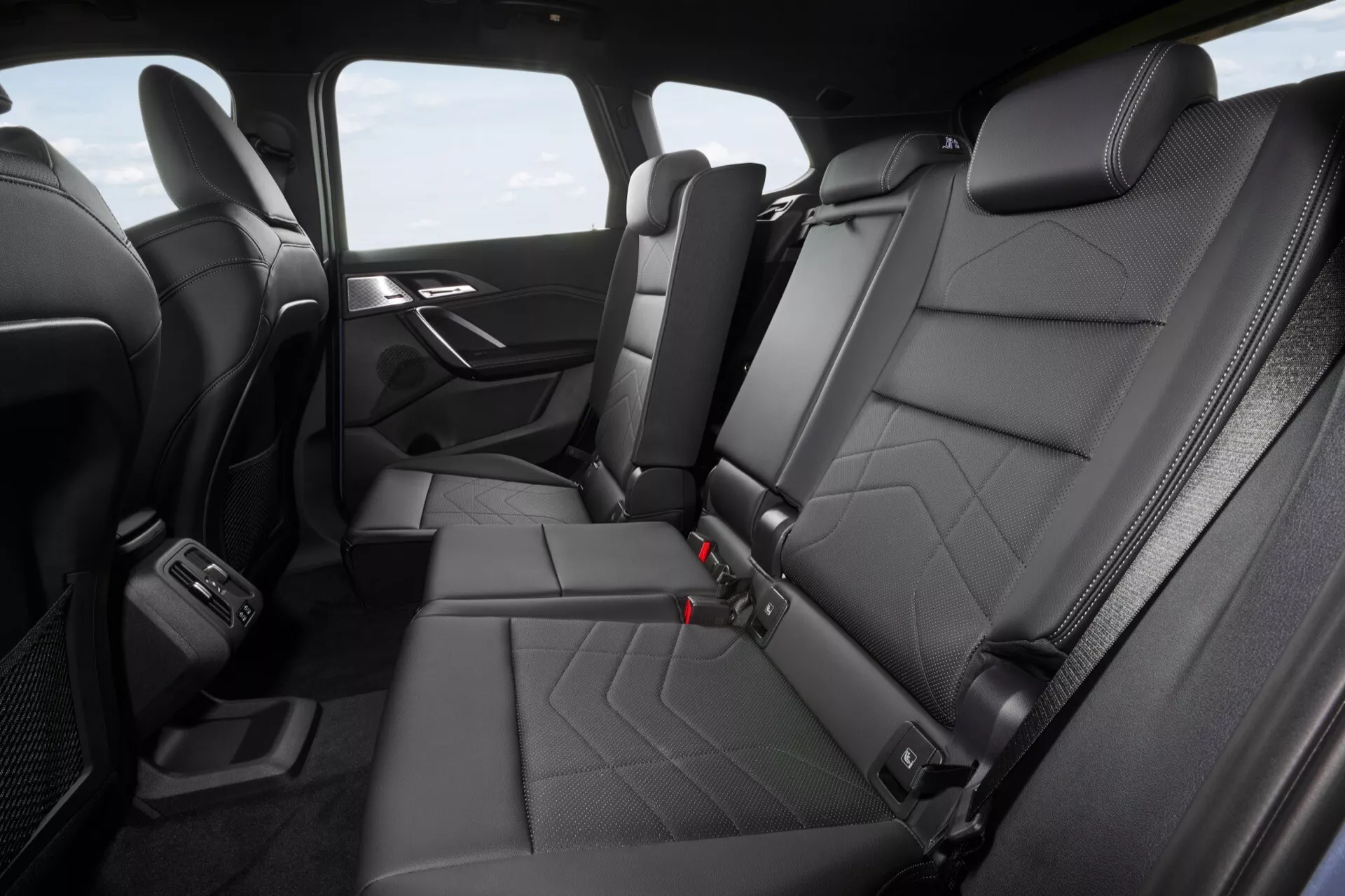 Lyxig interiörvy av BMW X1 (U11) 2022 som visar svarta läderbaksäten med quiltat mönster, ISOFIX-fästpunkter för barnstol, baksida AC-ventiler, USB-laddningsportar och premiumavslutningar