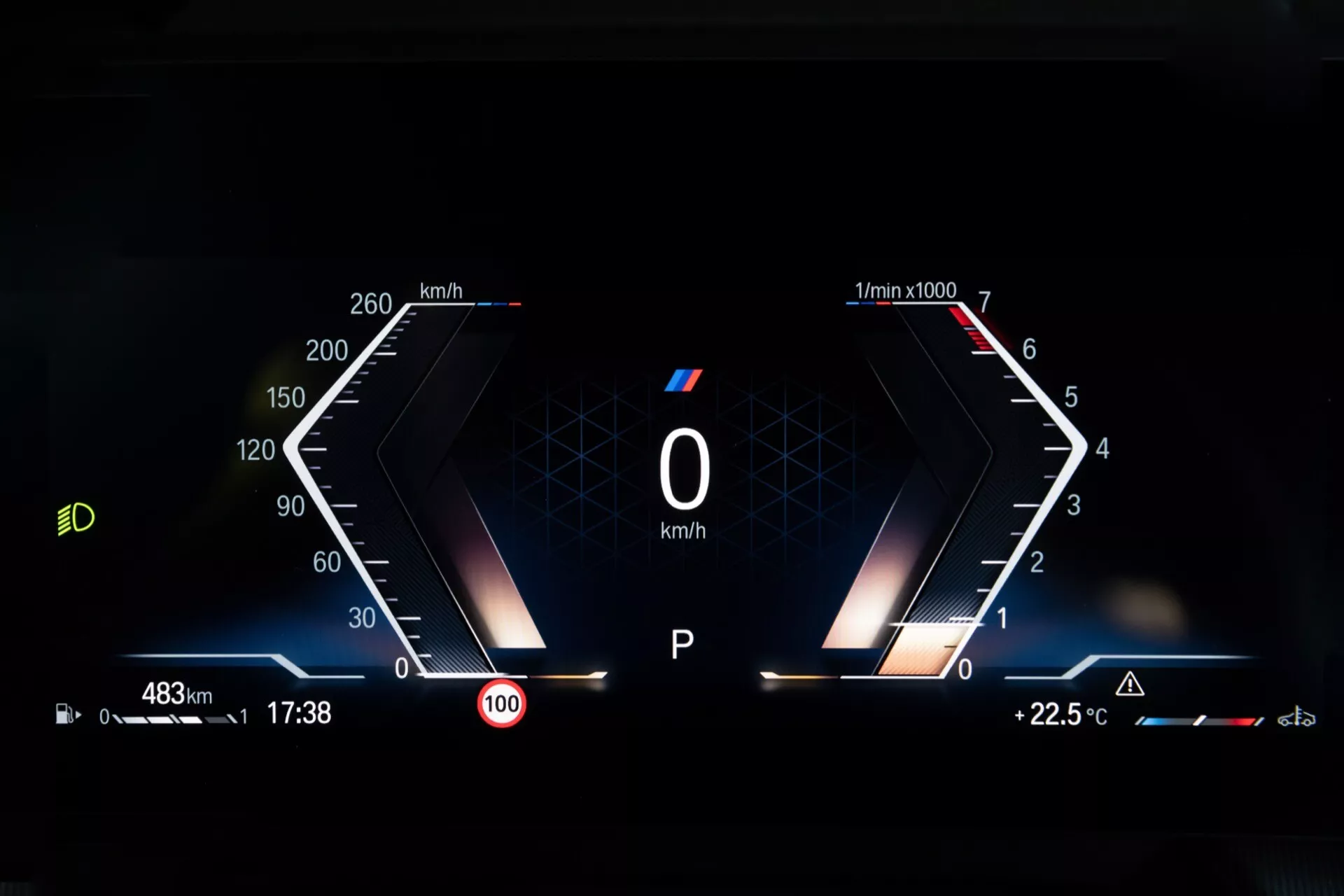 Interiörvy av BMW X1 (U11) 2022 med en modern digital instrumentpanel som visar hastighetsmätare, varvräknare, körsträcka, tid, hastighetsbegränsning, motortemperatur och olika teknologifunktionsindikatorer inklusive aktiv farthållare och varningar för filbyte, framhävd av prestandaorienterad 'M'-märkning