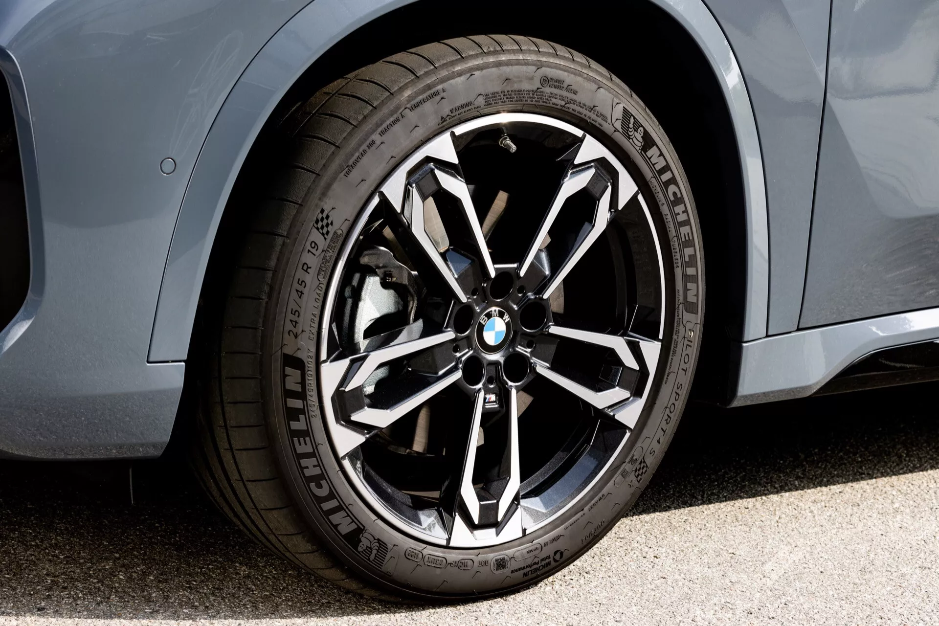 Närbild av framhjulet och sidosektionen av BMW X1 2022 (U11), med ett fler-ekrat lättmetallhjul med BMW-logotyp, Michelin-prestandadäck och metalliclackfinish