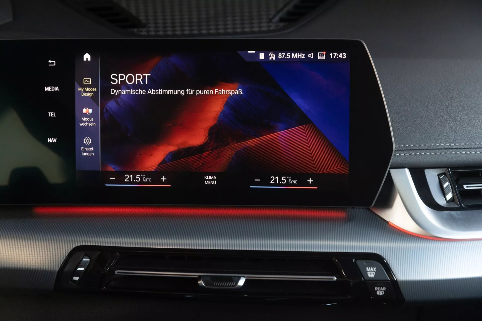 Interiör av BMW X1 (U11) 2022 som visar en högupplöst infotainment-skärm i sportläge, integrerad klimatkontroll och tvåtonig instrumentbräda med röda accenter