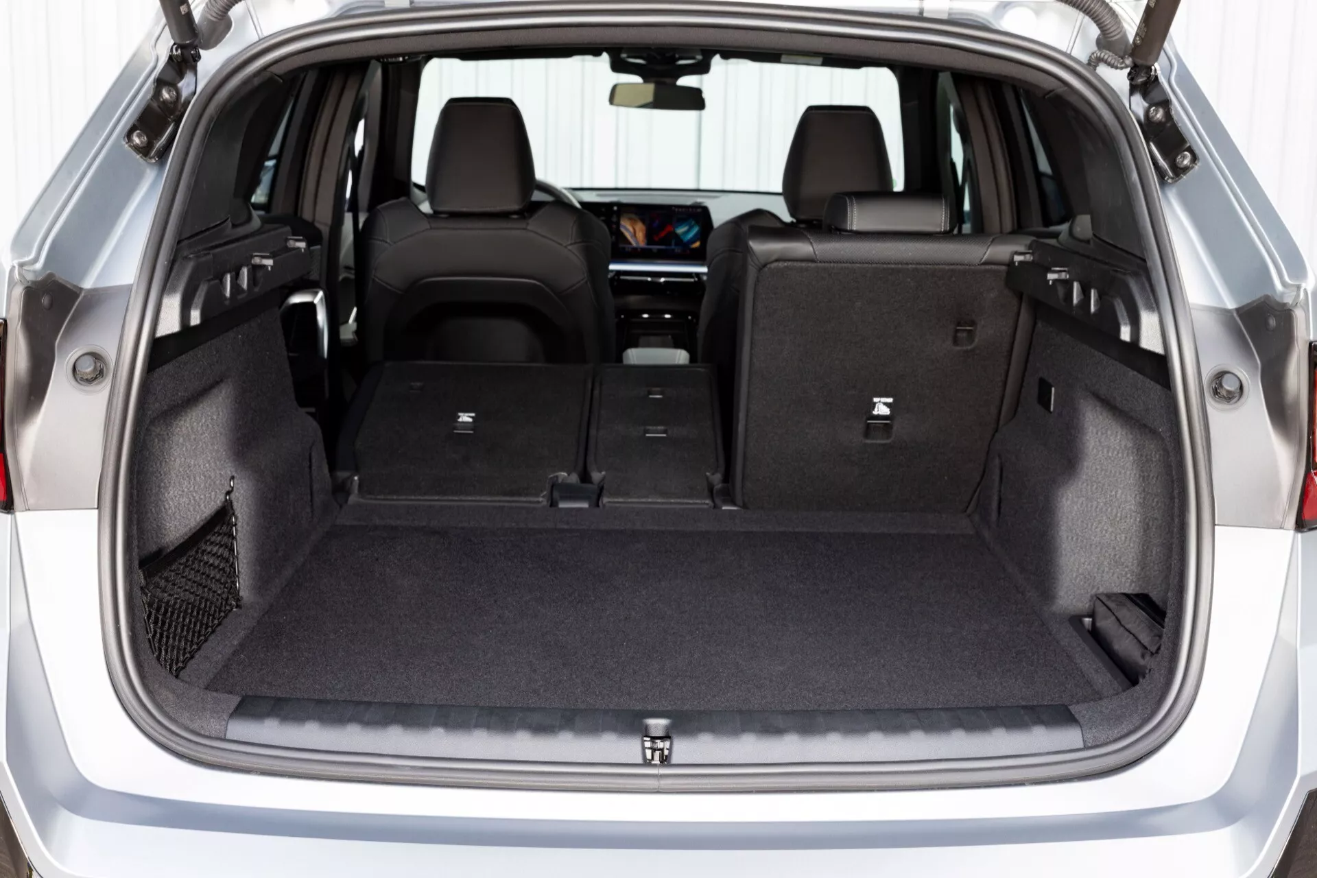 Fotografi av BMW X1 (U11) 2022 som visar det omfattande lastutrymmet med nedfällda baksäten, sett från bagageluckan med detaljer om förvaringsfack och surrningskrokar