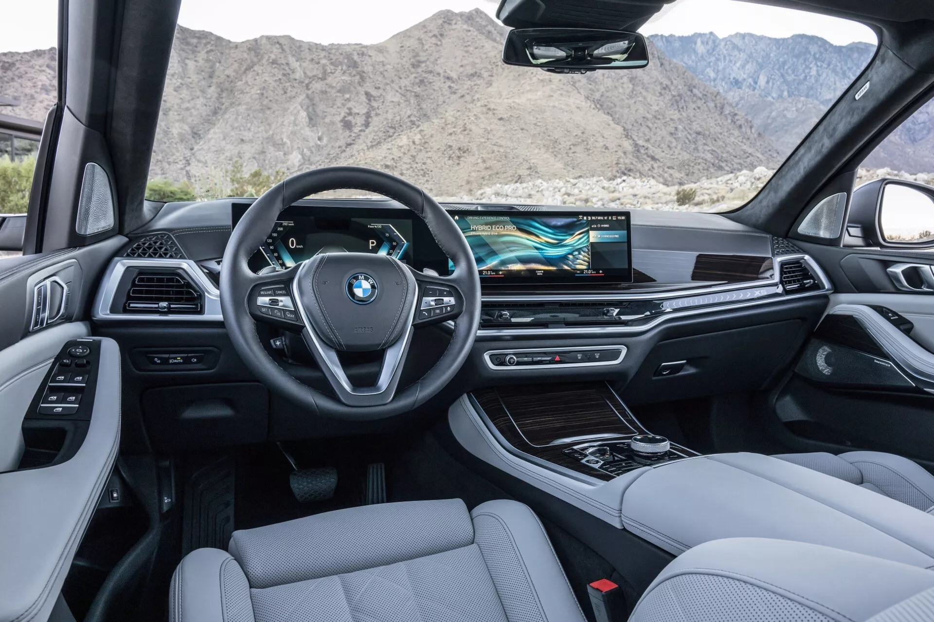 Interiörvy från baksätet i BMW X5 2023 (G05-F95-Facelift) visar instrumentpanelen, ratten, mittkonsolen och framsätena, utrustad med modern teknik och lyxig design