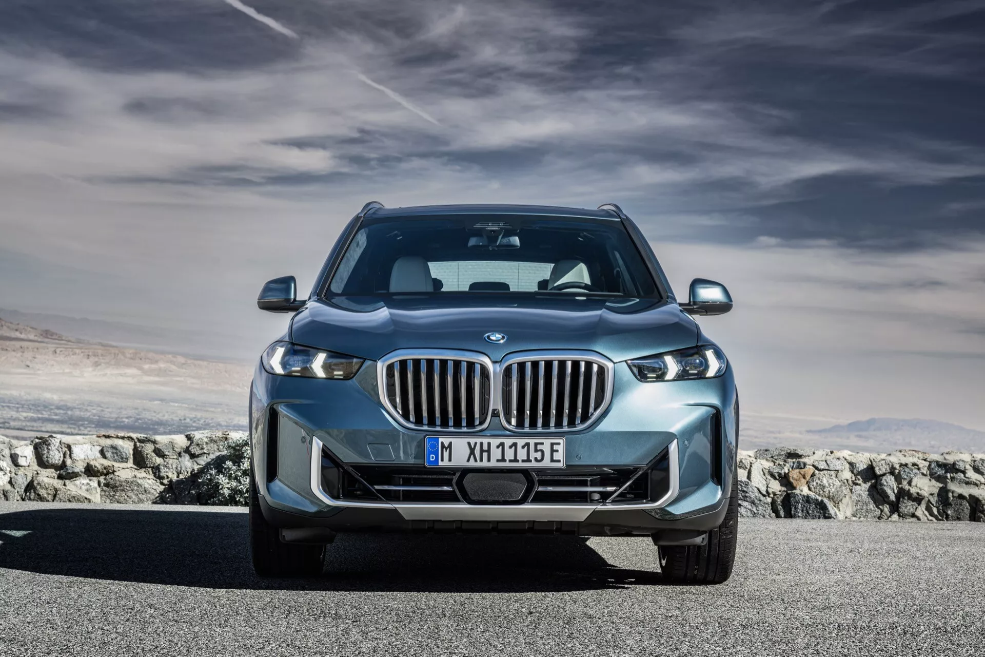 Lågvinklad framtida vy av en BMW X5 2023-modell, som visar upp distinkt njurgrill, LED-strålkastare och aerodynamisk design, med blå accent som indikerar elektrifiering