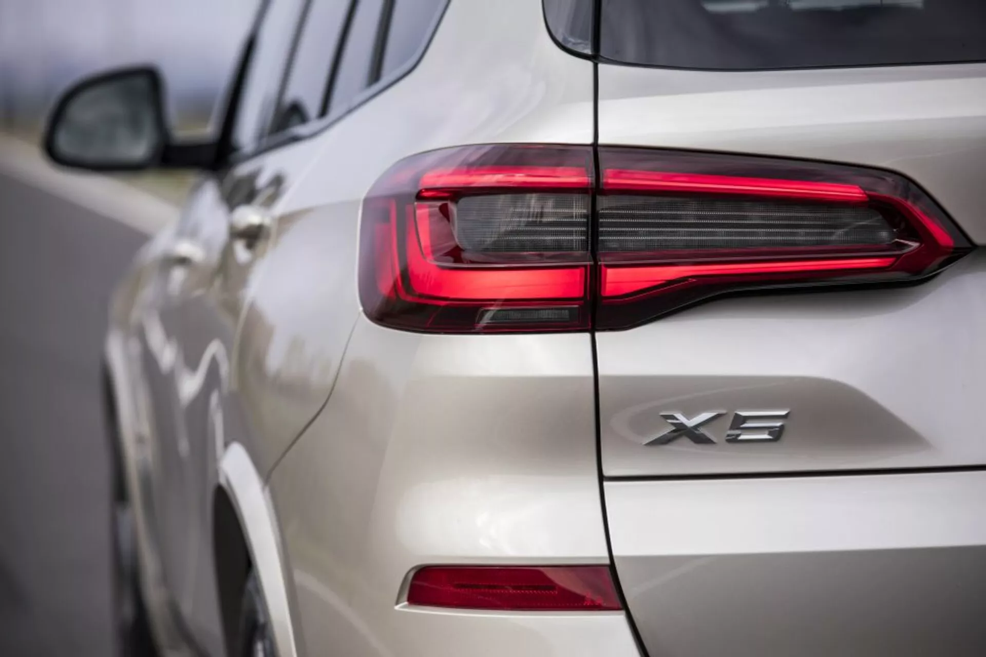 Närbild av baksidan på en vit BMW X3 2018, som visar upp LED-baklyktans design och X3-emblemet, med fokus på den moderna, horisontella ljussignaturen och invecklade detaljer på bakluckan och sidan.