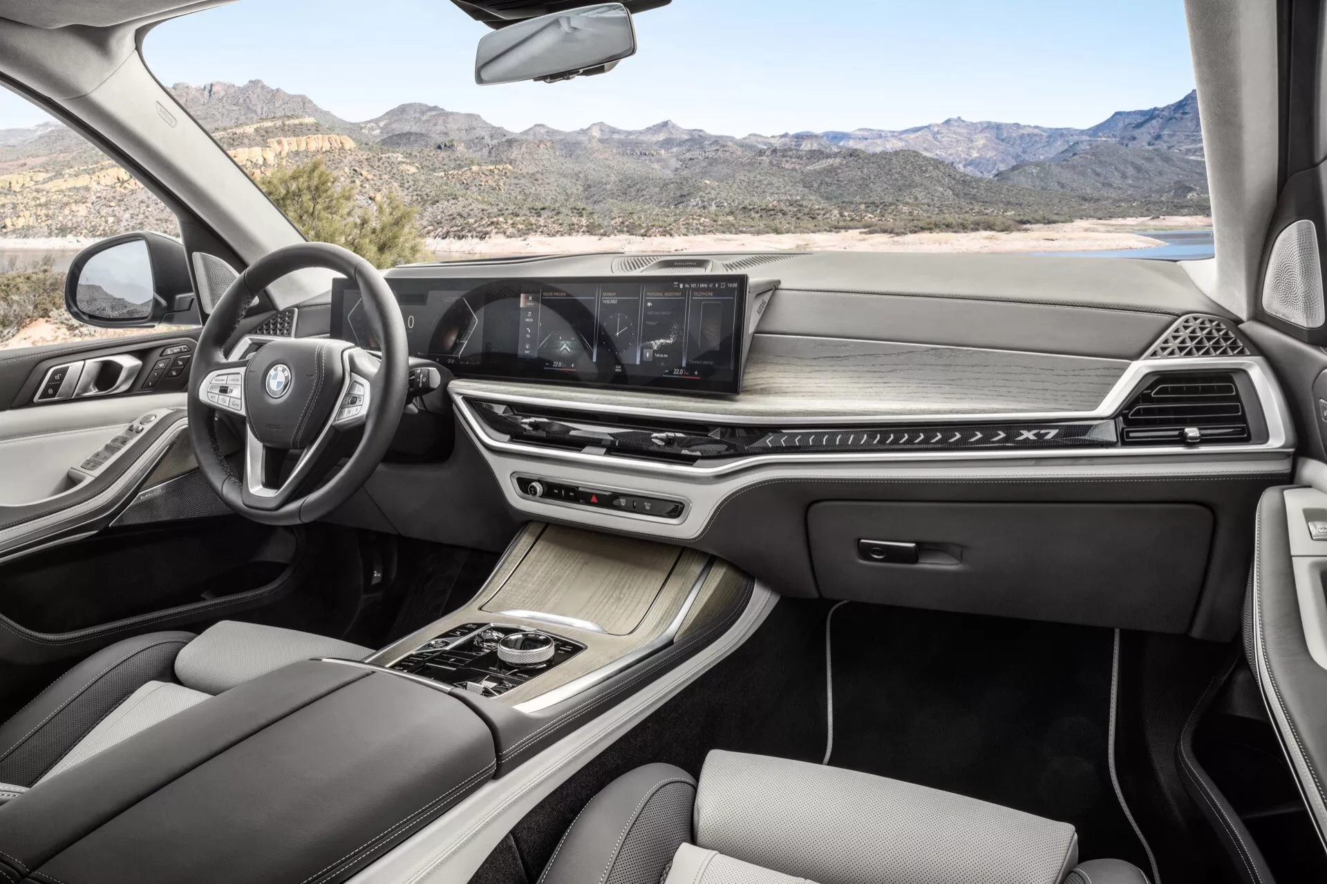 Interiör av BMW X7 2022 (G07-facelift) med multifunktionsratt, avancerat infotainmentsystem med pekskärm, dubbelzons klimatkontroll, elegant automatisk växelspak, lyxiga lädersäten med kontrastsömmar, och panoramatak