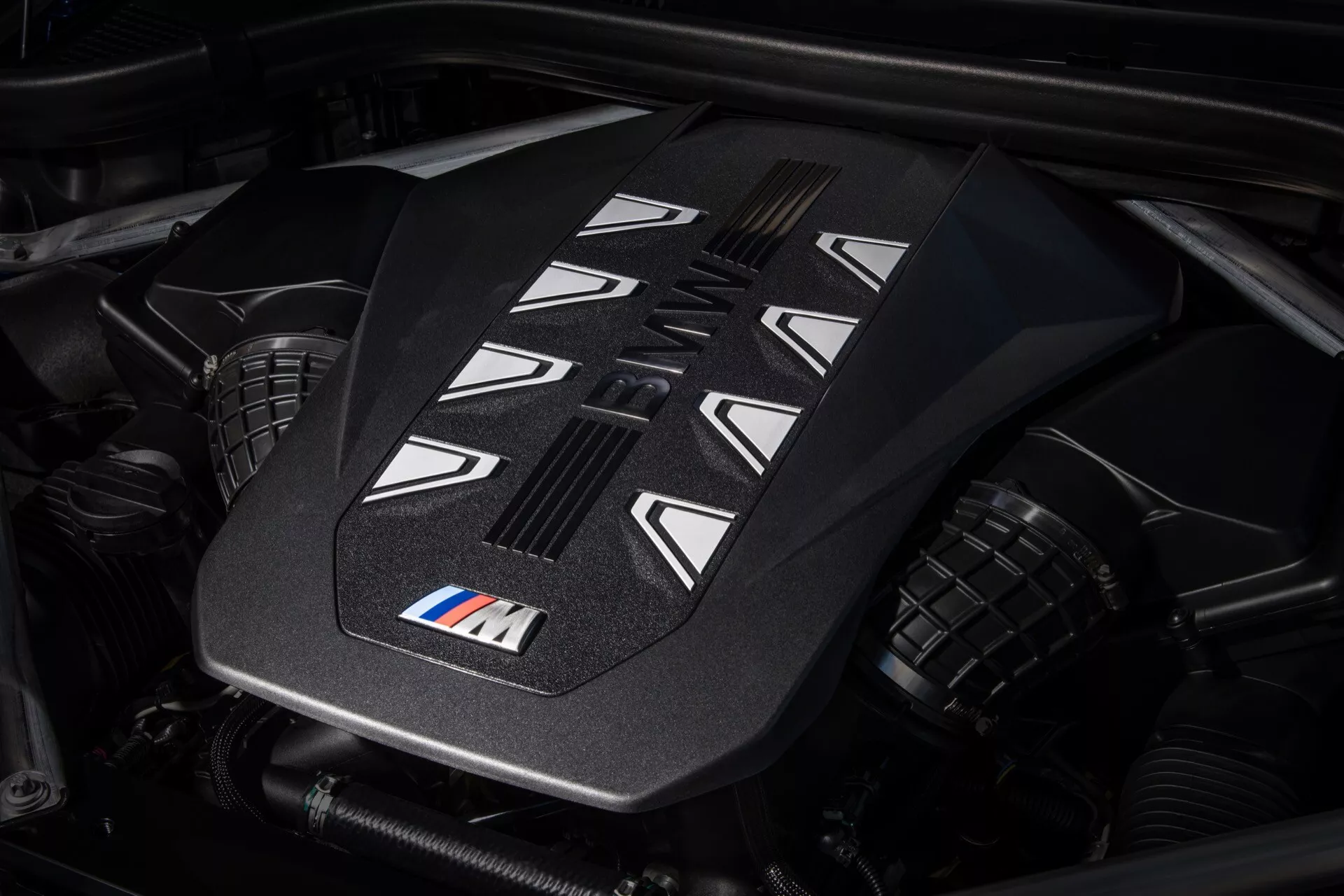 Närbild av högprestanda motorlocket på BMW X7 2022 (G07-Facelift) med M-märke, som visar avancerade designdetaljer och kylningsskåror