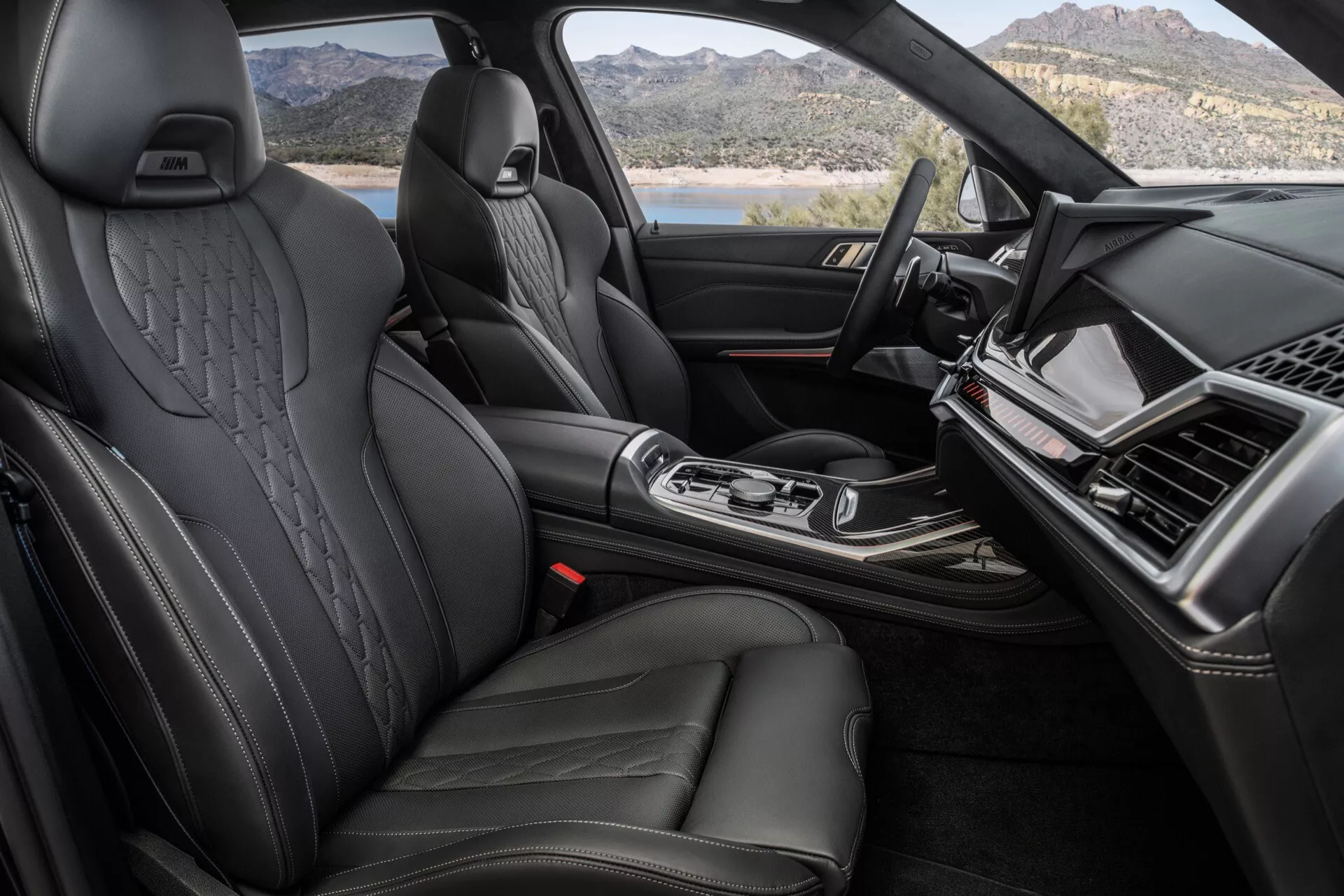 Interiörvy av BMW X7 2022 (G07-Facelift) med fokus på den premium främre kabinen med svarta lädersäten som har sidostöd och präglade nackstöd, snygg instrumentbräda med infotainment-skärm, central konsol med ergonomisk växelspak och högkvalitativa finishar som indikerar en lyxbil.