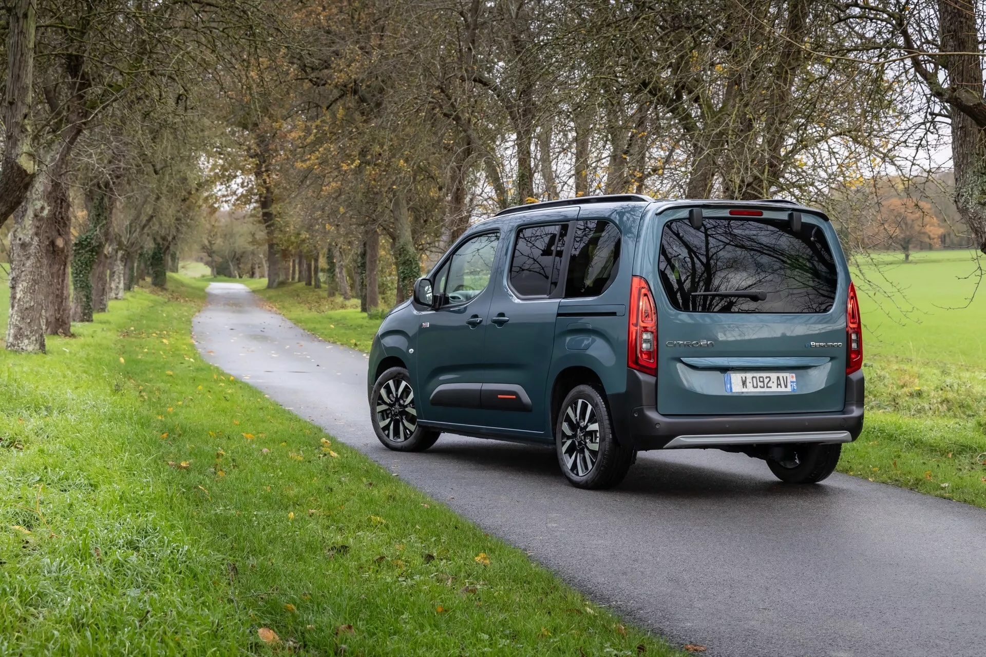 Bakre tre fjärdedels vy av Citroen Berlingo 3:e generation facelift 2024 på landsväg, med europeiskt registreringsskylt, bakre vindrutetorkare och modern bakljusdesign.
