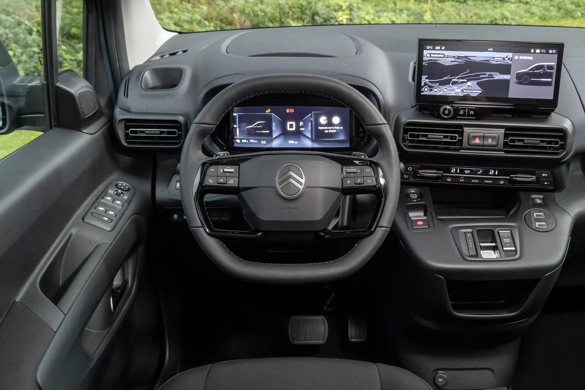 Interiör av Citroen Berlingo 2024 (3:e generationens ansiktslyft) som visar förarens perspektiv på den digitalt orienterade instrumentbrädan, med en multifunktionell tre-eker ratt, digital instrumentkluster, pekskärms infotainmentsystem och avslutningar av högkvalitativa material.