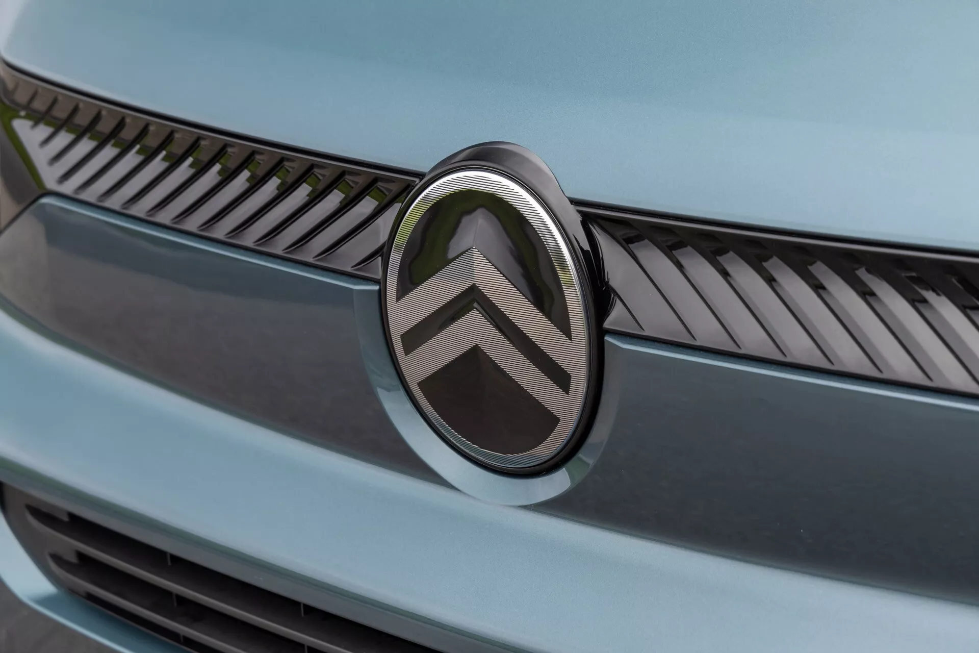 Närbild av Citroën Berlingo 2024 facelift framsektion som visar den dubbla chevron-logotypen och detaljerad grilldesign med metalliska avslutningar under mjuk belysning