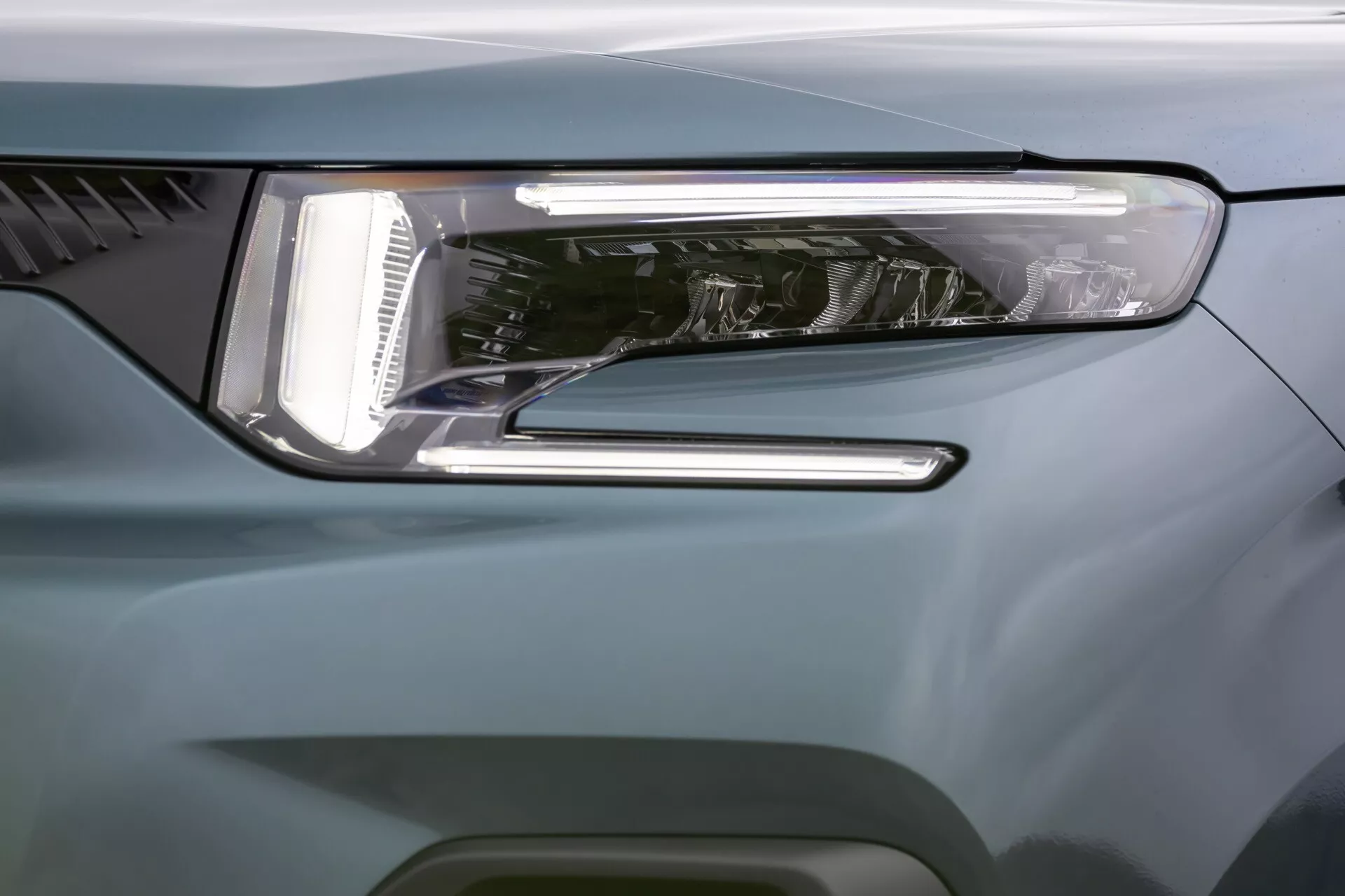 Närbild av framkanten på Citroen Berlingo 2024 som framhäver modernt LED-strålkastardesign, LED-dagsljus, sekundär ljusfunktion och aerodynamiskt blågrå kaross