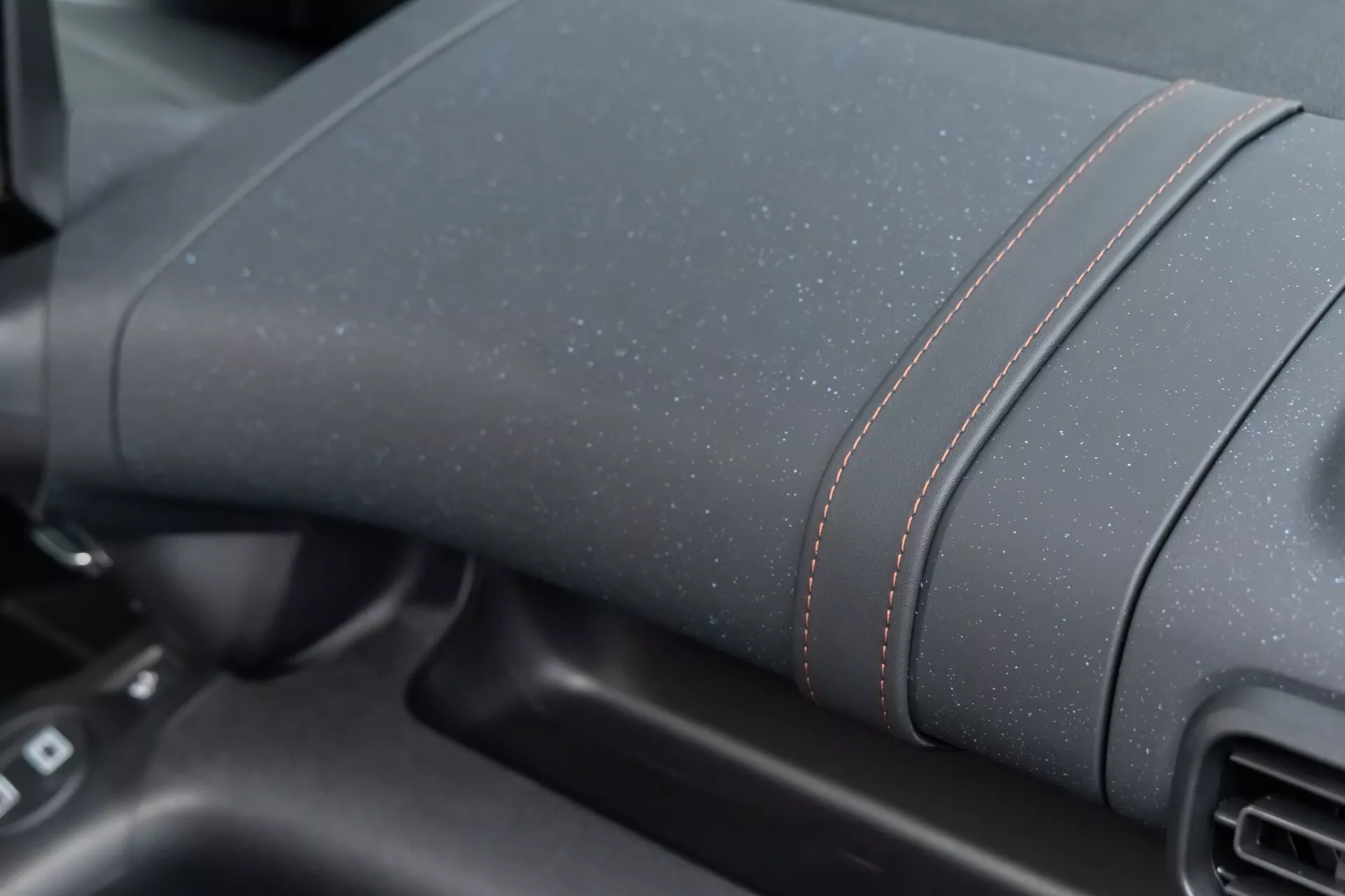 Närbild av instrumentbrädan till Citroen Berlingo 2024 (3:e generationens ansiktslyft) som visar texturerat mörkt material med kontrasterande röda sömmar, utan synliga teknikelement