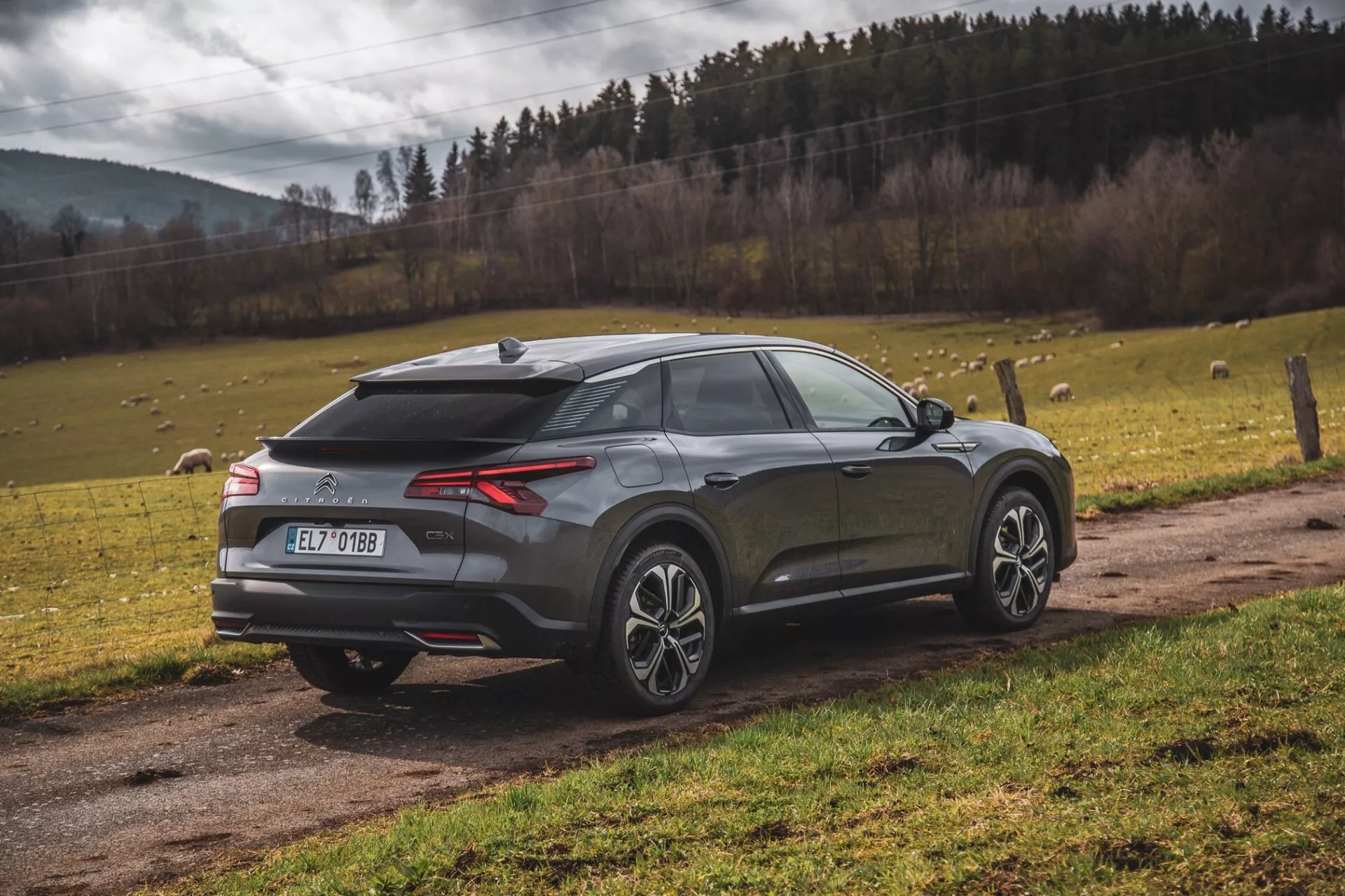 2022 Citroen C5-X modern crossover SUV parkerad utomhus, bakifrån tre fjärdedels vy som framhäver LED-bakljus, bakre diffusor, parkeringssensorer eller kamera, hajfen-antenn, tvåtonade legeringshjul, sluttande bakruta, integrerad spoiler och metallic finish, inställd mot en naturlig landskapsbakgrund